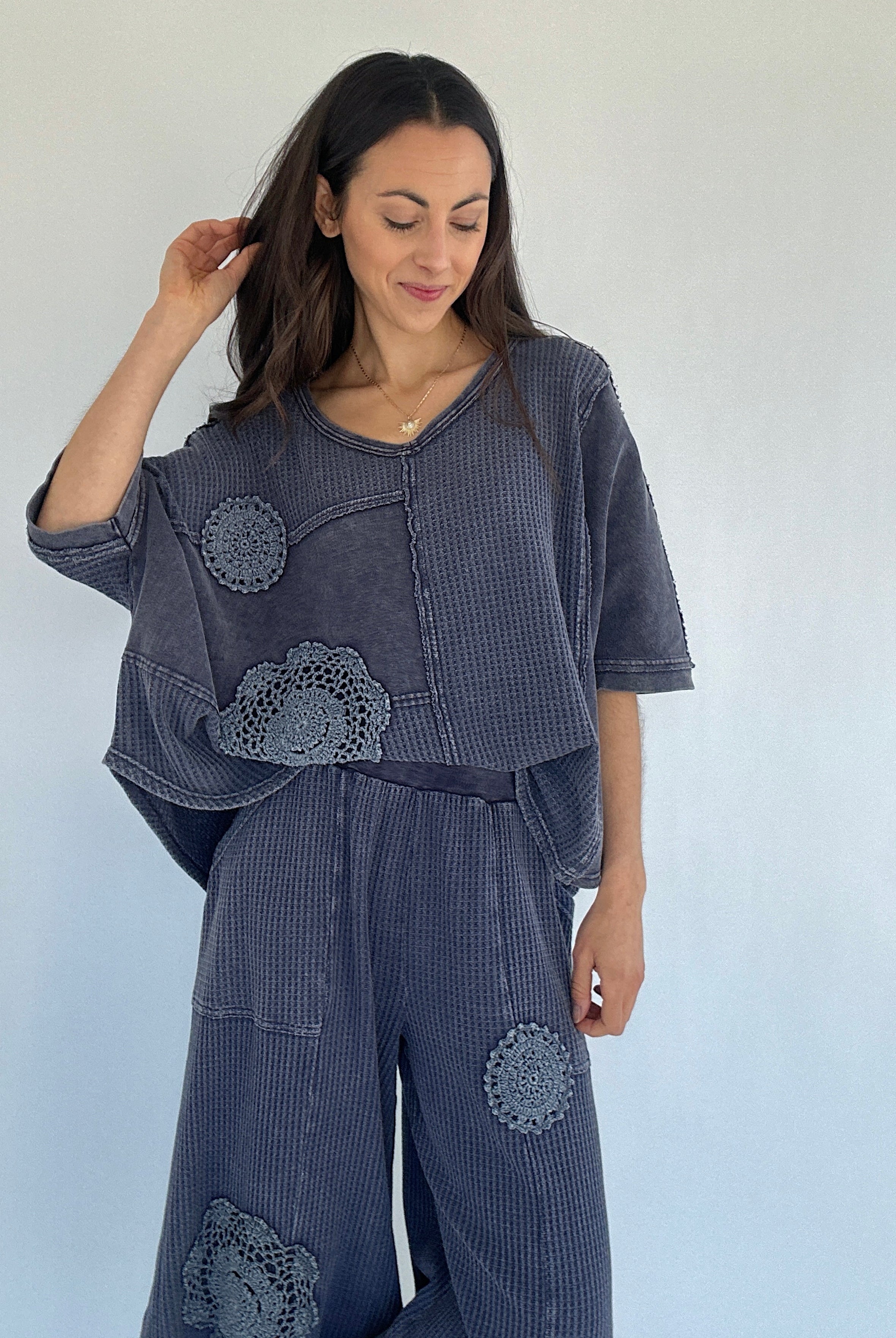 Woman wearing a dark blue waffle knit outfit with floral crochet patterns against a white background