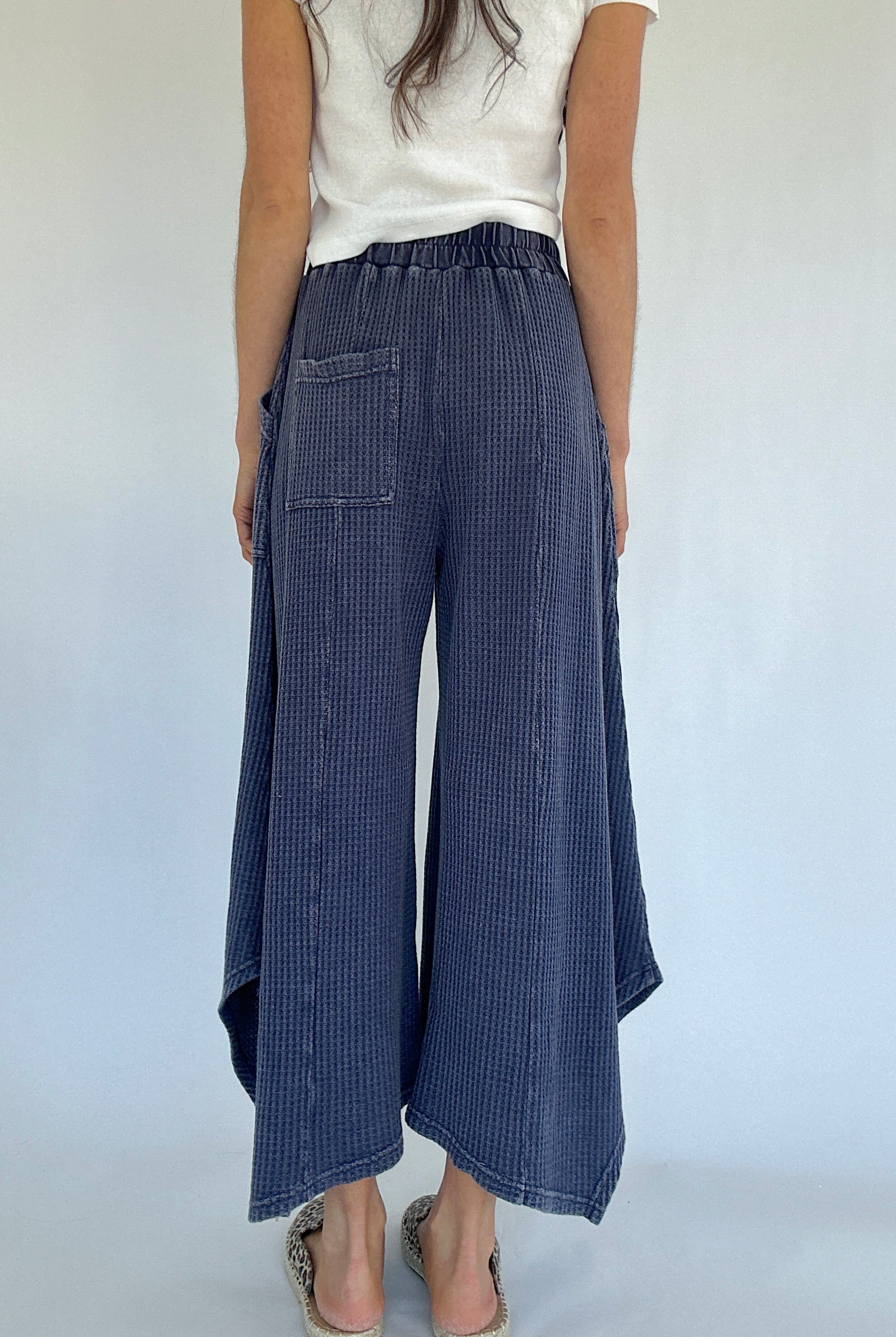Person wearing blue waffle knit wide-leg pants on a white background showing back with one back pocket