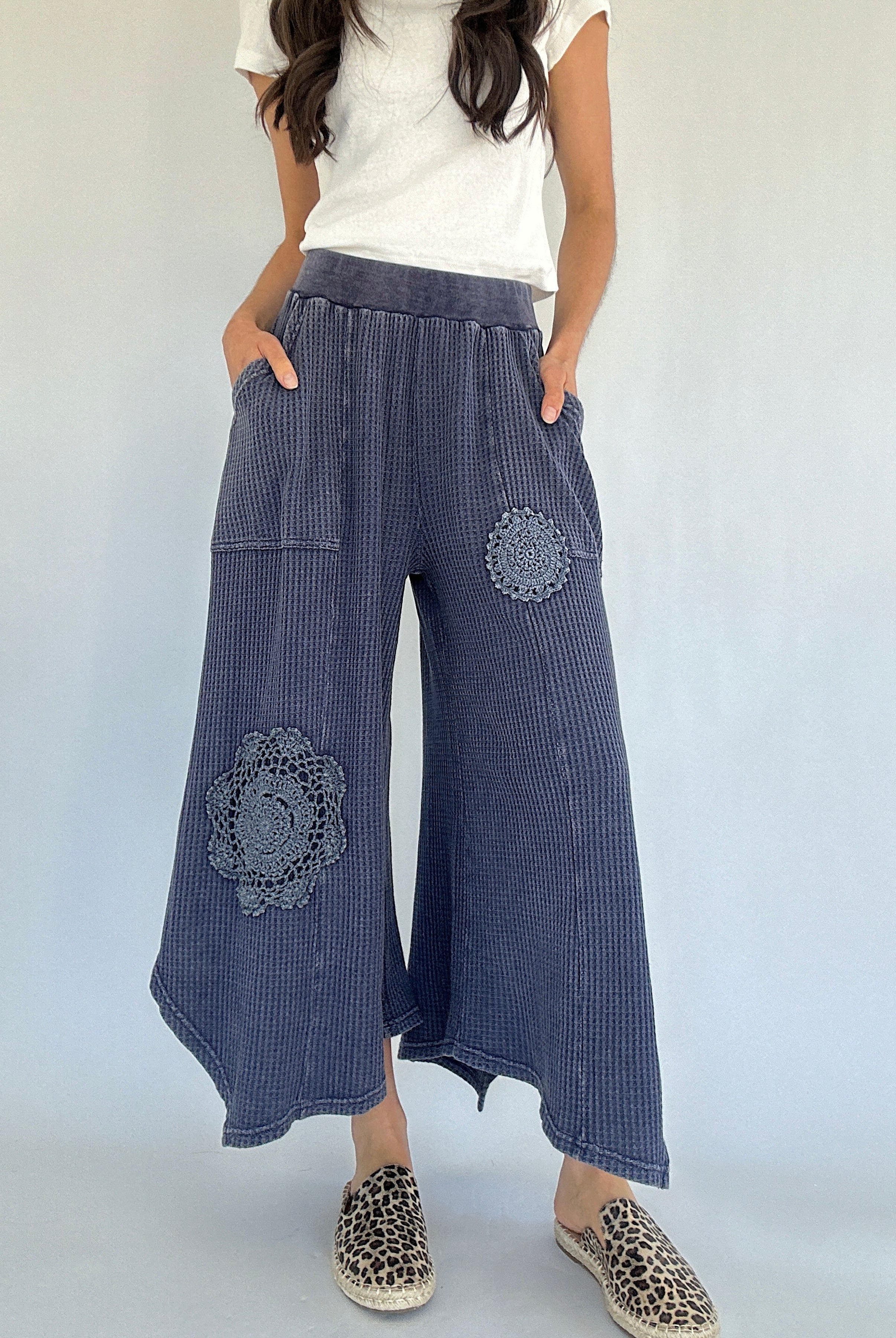 Person wearing midnight blue waffle knit wide-leg pants with floral patches on a white background
