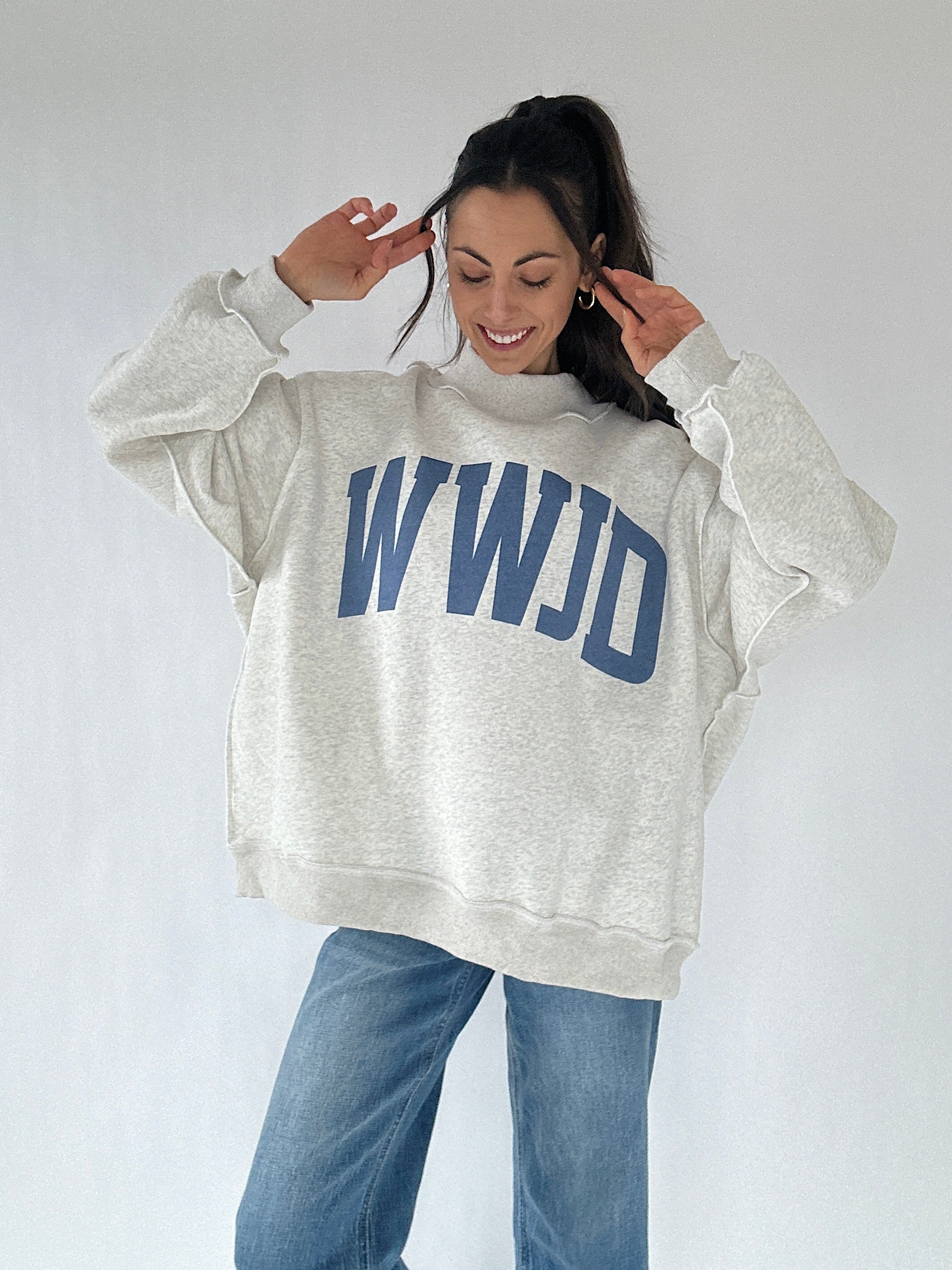 Person wearing a gray sweatshirt with 'WWJD' text on a plain background