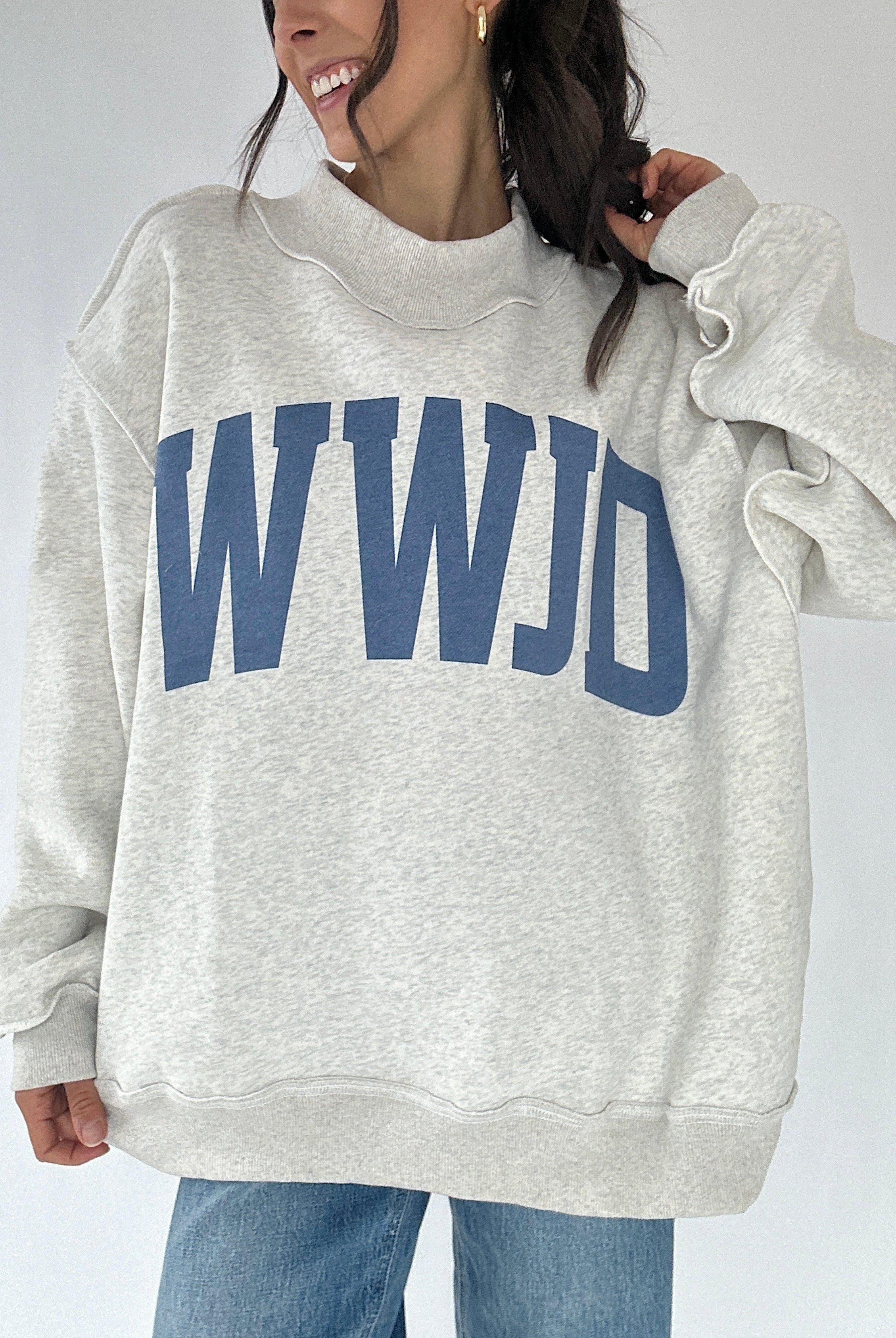 Person wearing a gray sweatshirt with 'WWJD' printed in blue on a plain background