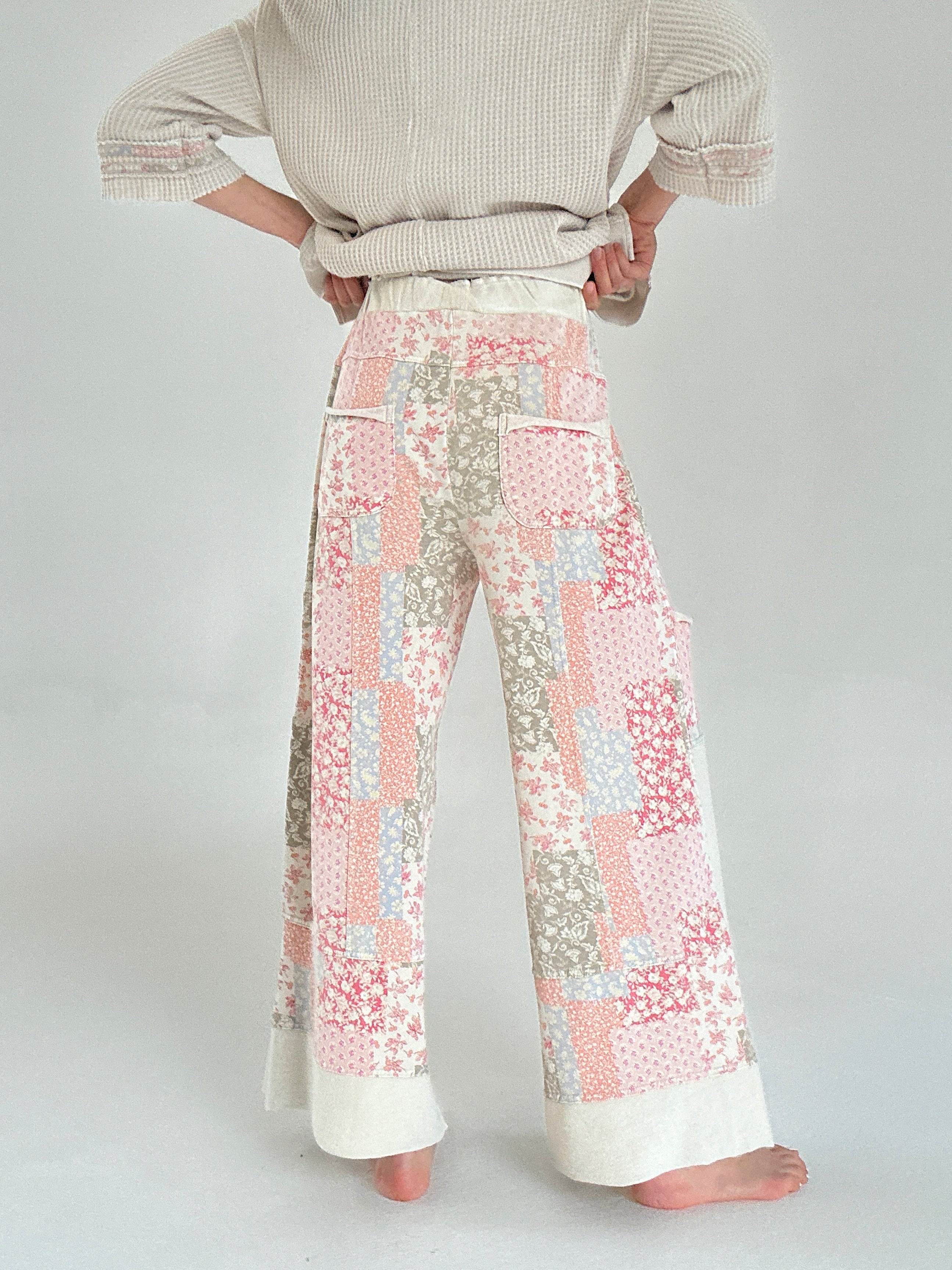 Person wearing a patterned pants and beige sweater on a plain background from back