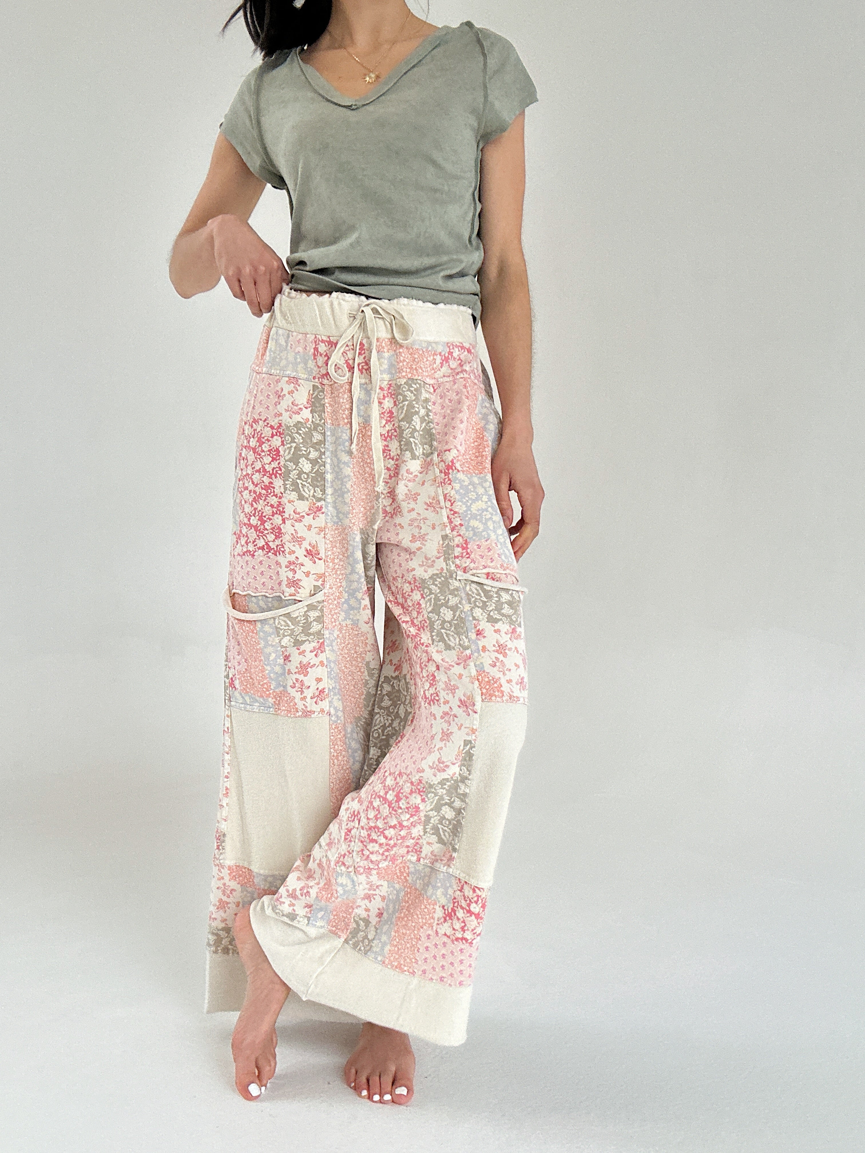 Person wearing a green top and floral patchwork pants on a plain background