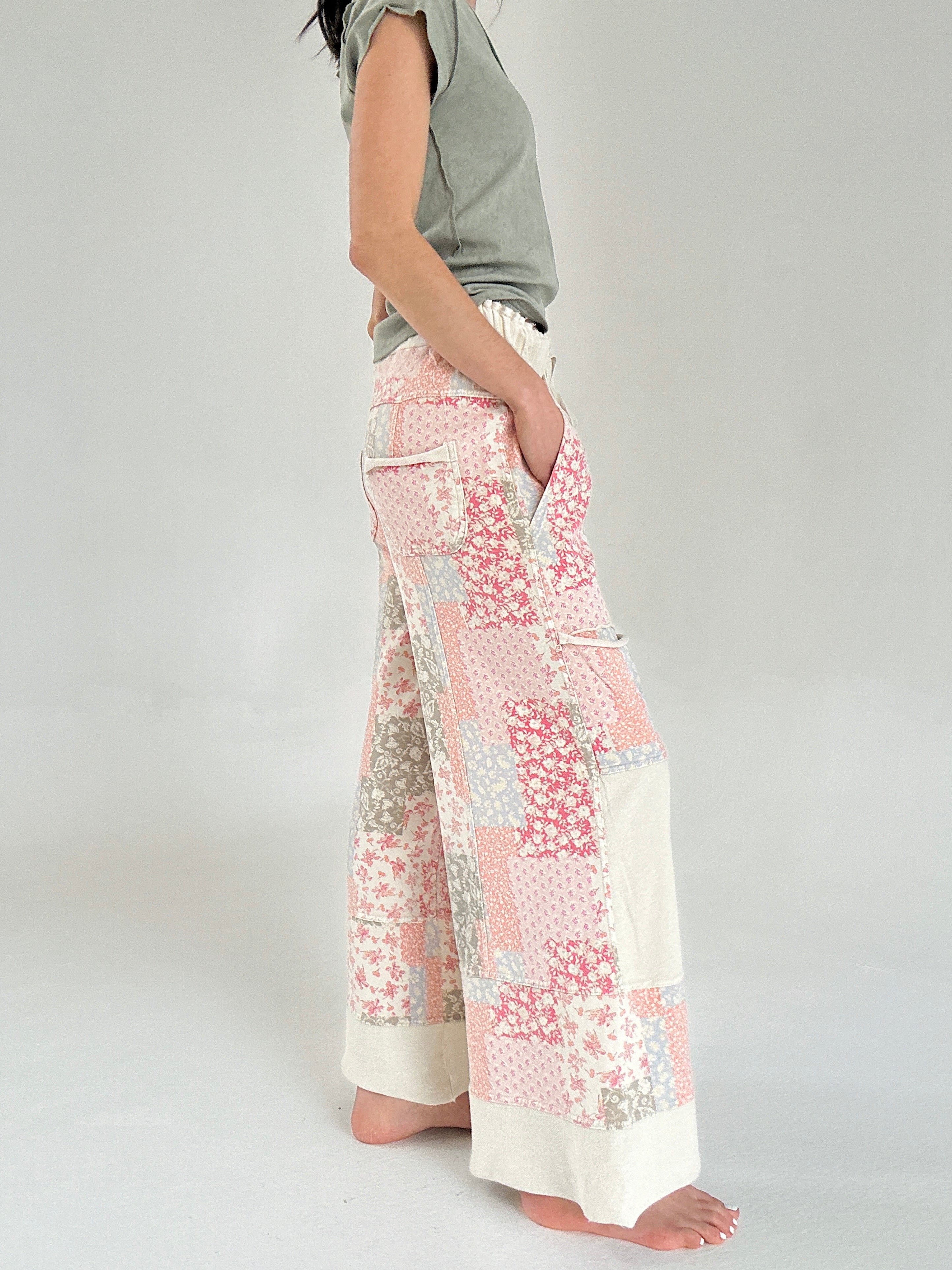 Person wearing floral patchwork pants on a plain background from side