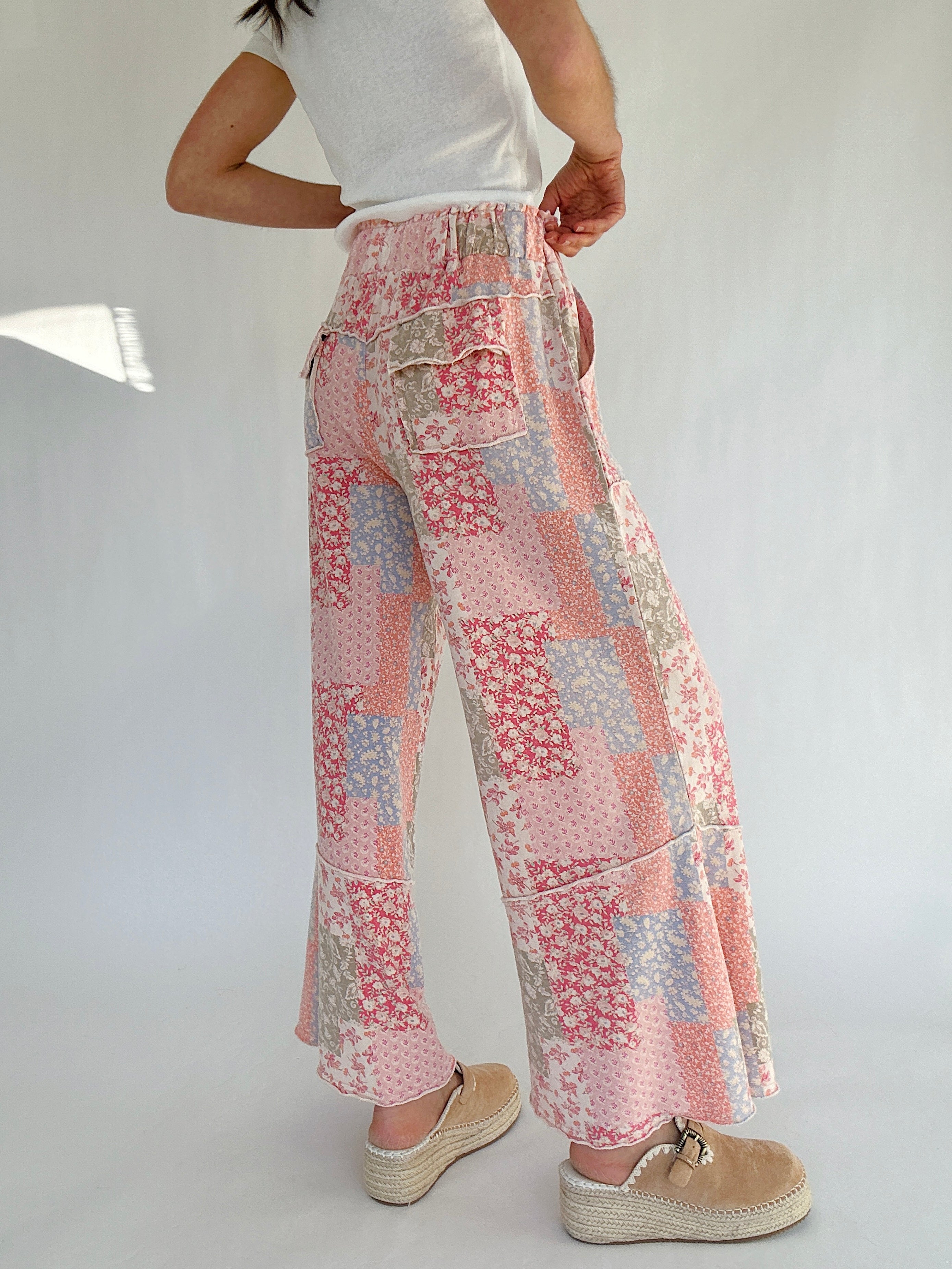 Person wearing floral patchwork pants on a plain background showing back cargo pockets