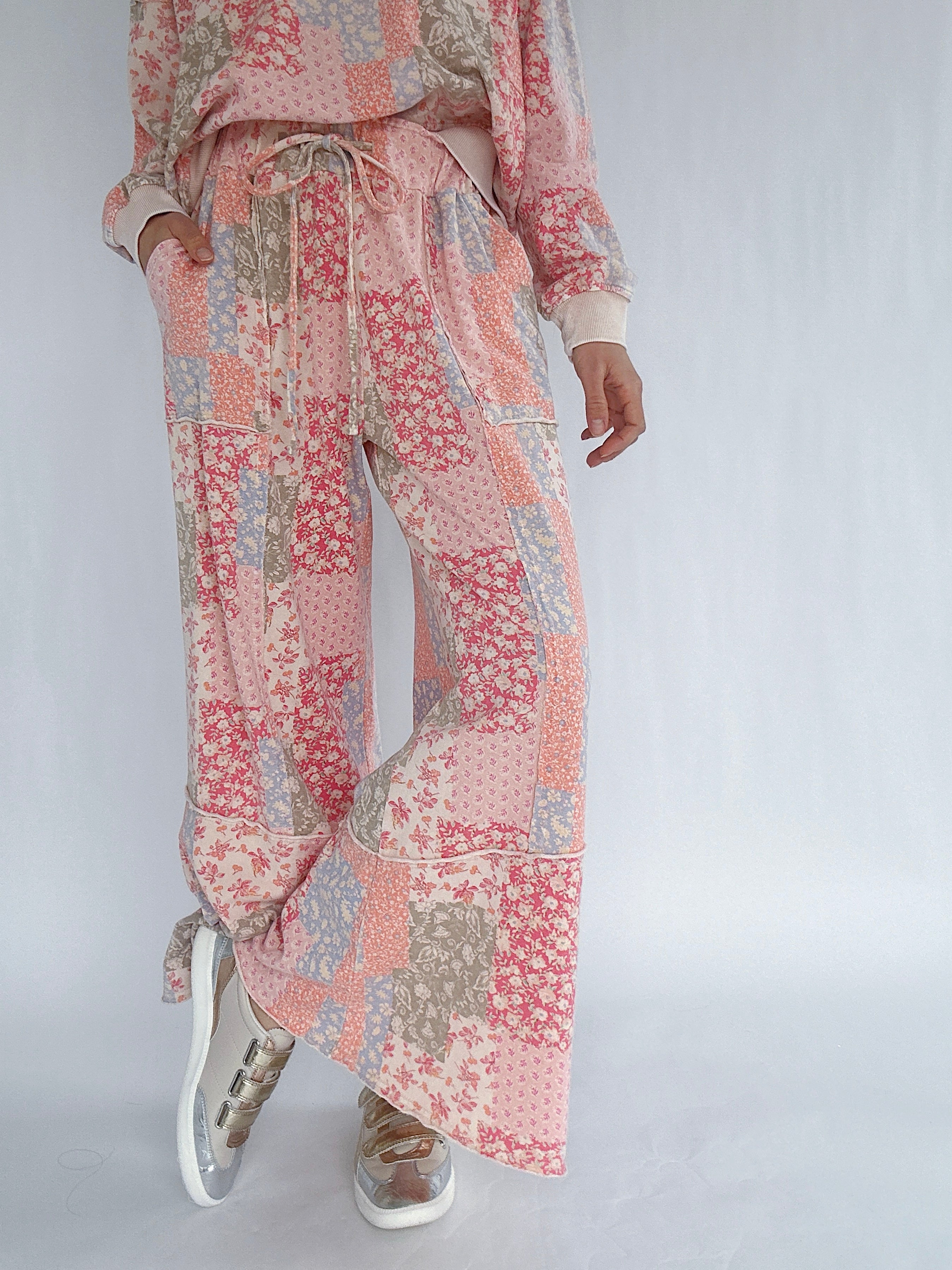 Person wearing a floral patterned outfit on a plain background showing wide leg pants