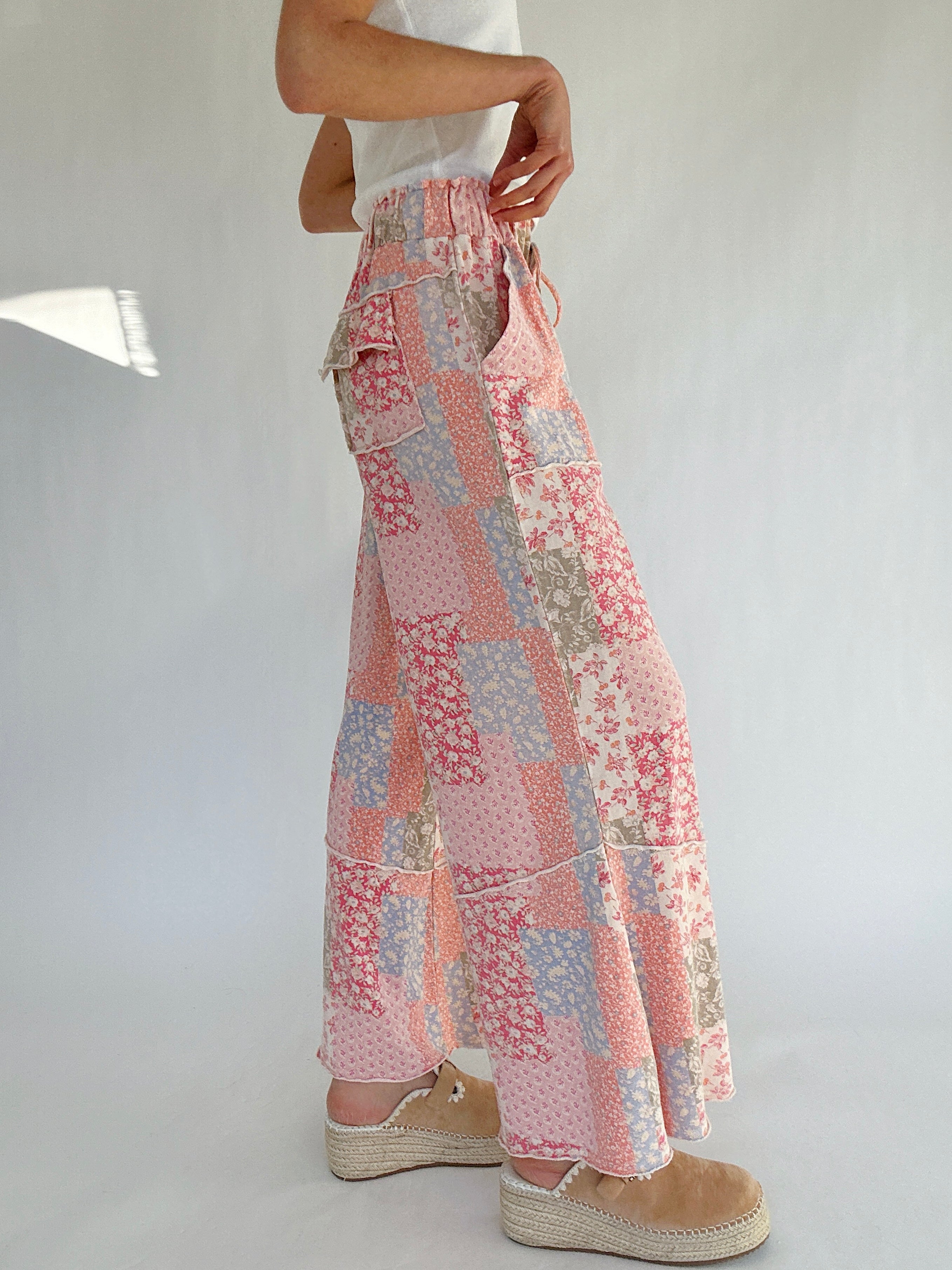 Person wearing a patchwork patterned pants on a plain background from the side