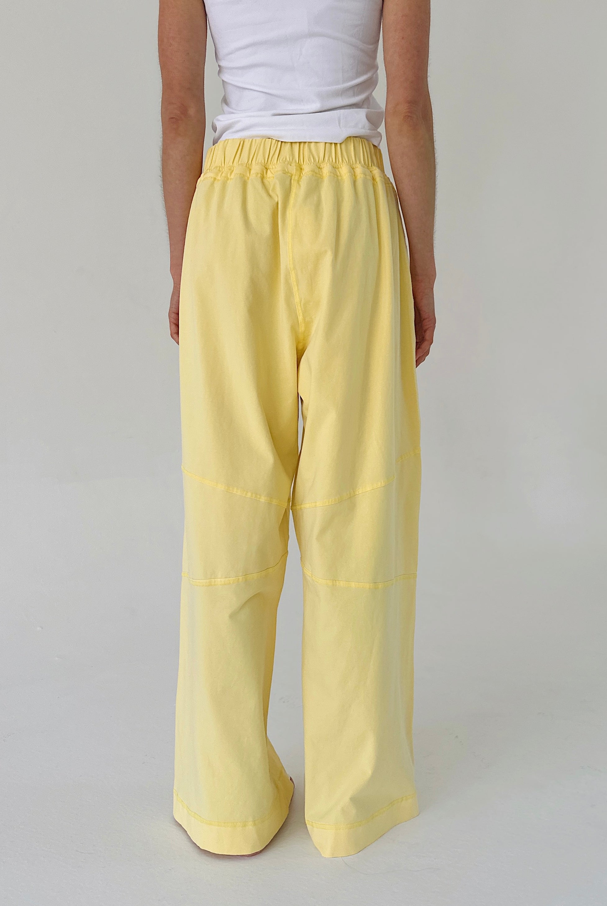 Person wearing yellow pants and a white top on a plain background