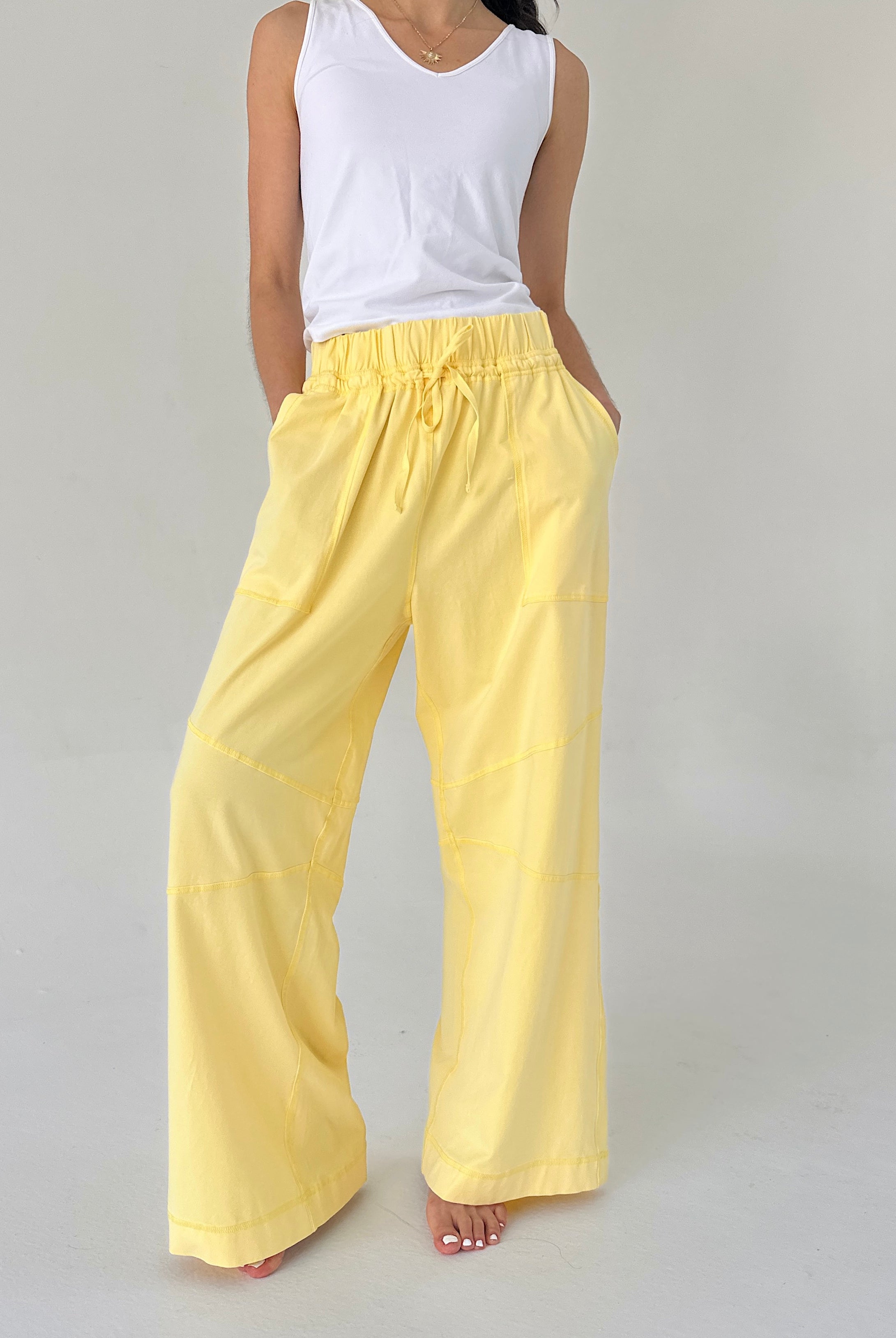 Person wearing yellow pants and a white top on a gray background