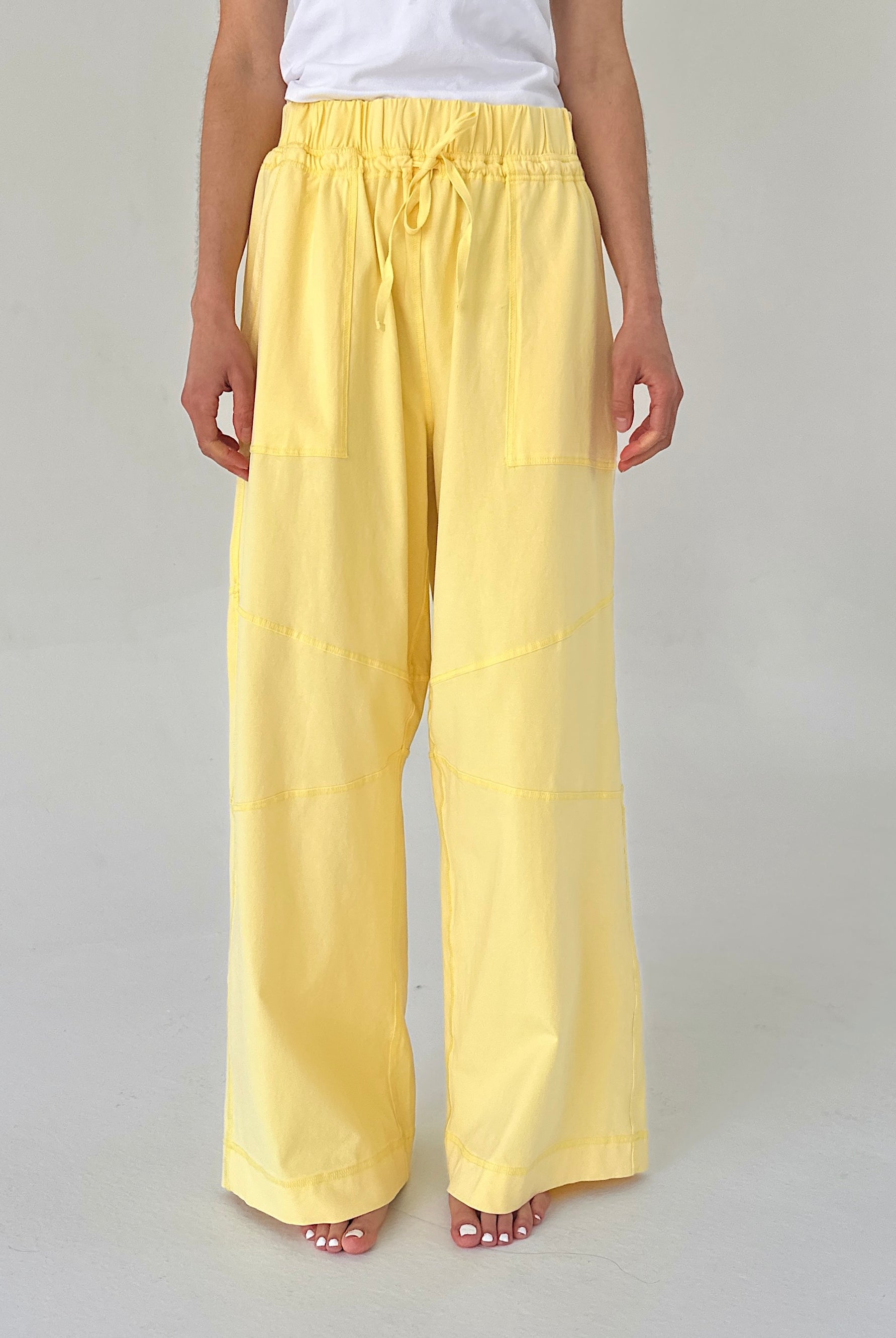 Person wearing yellow wide-leg pants on a plain background