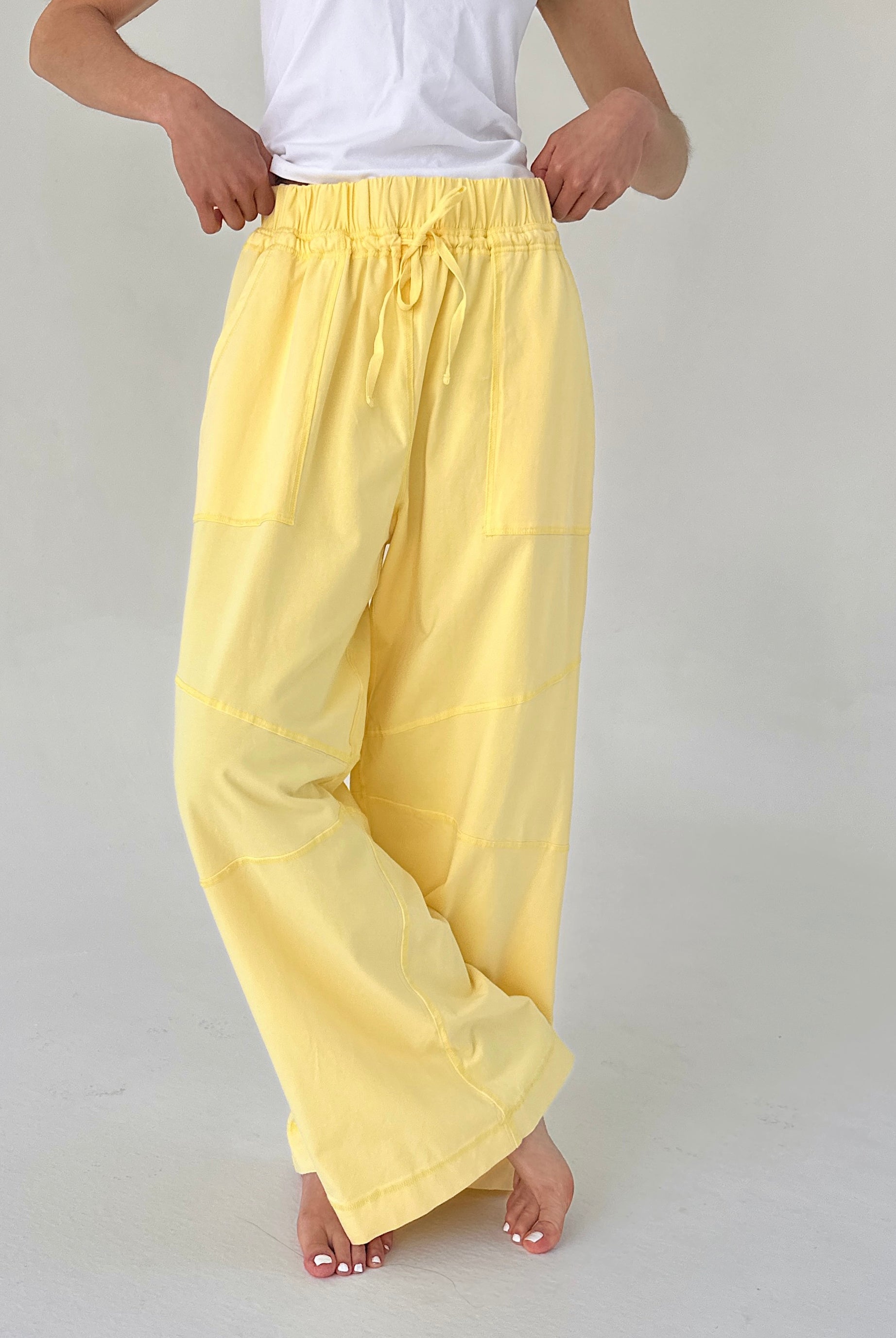 Person wearing yellow pants and a white top on a plain background
