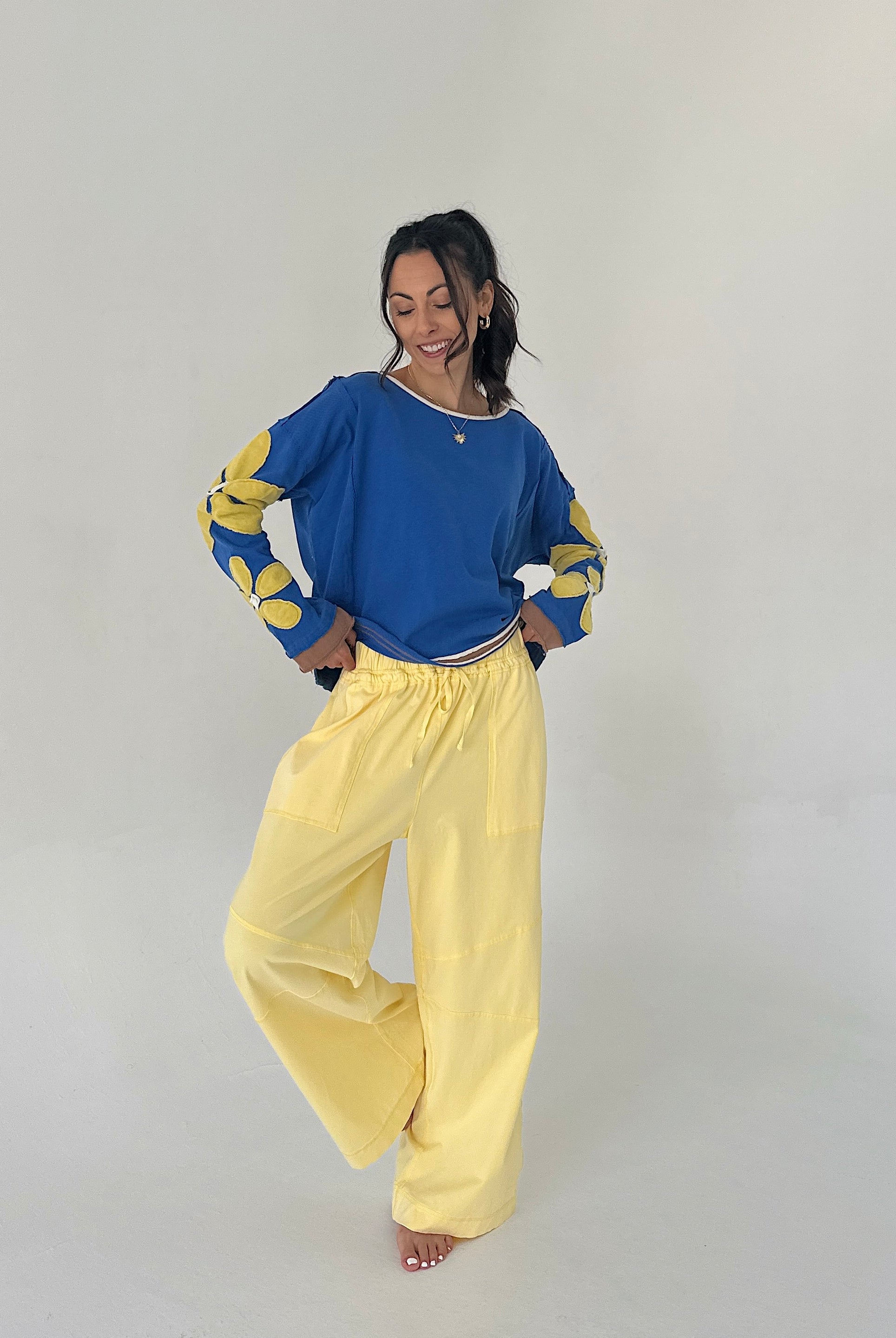 Person wearing a blue top with yellow sleeves and yellow pants on a plain background