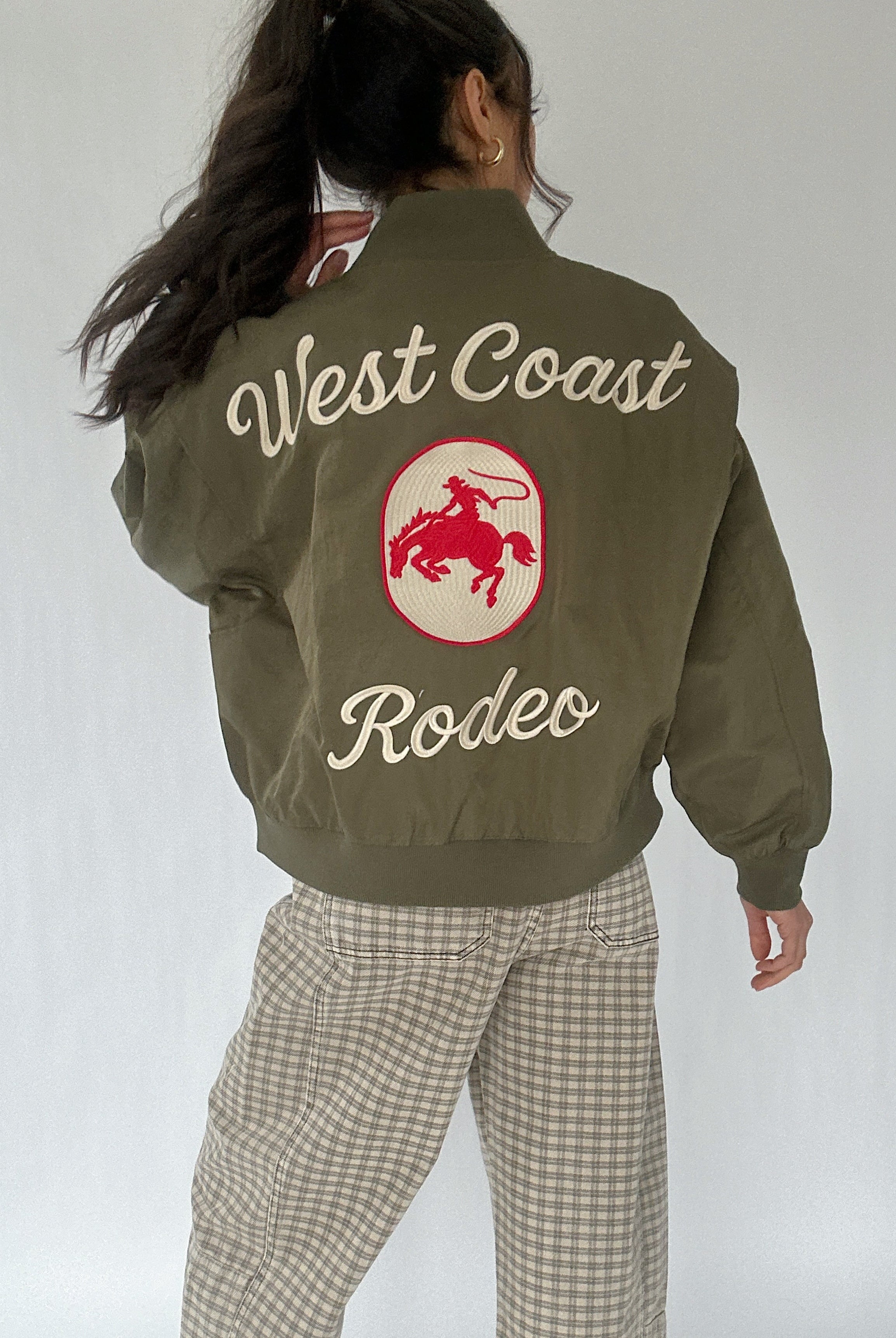 Person wearing a green jacket with 'West Coast Rodeo' text and logo on the back.
