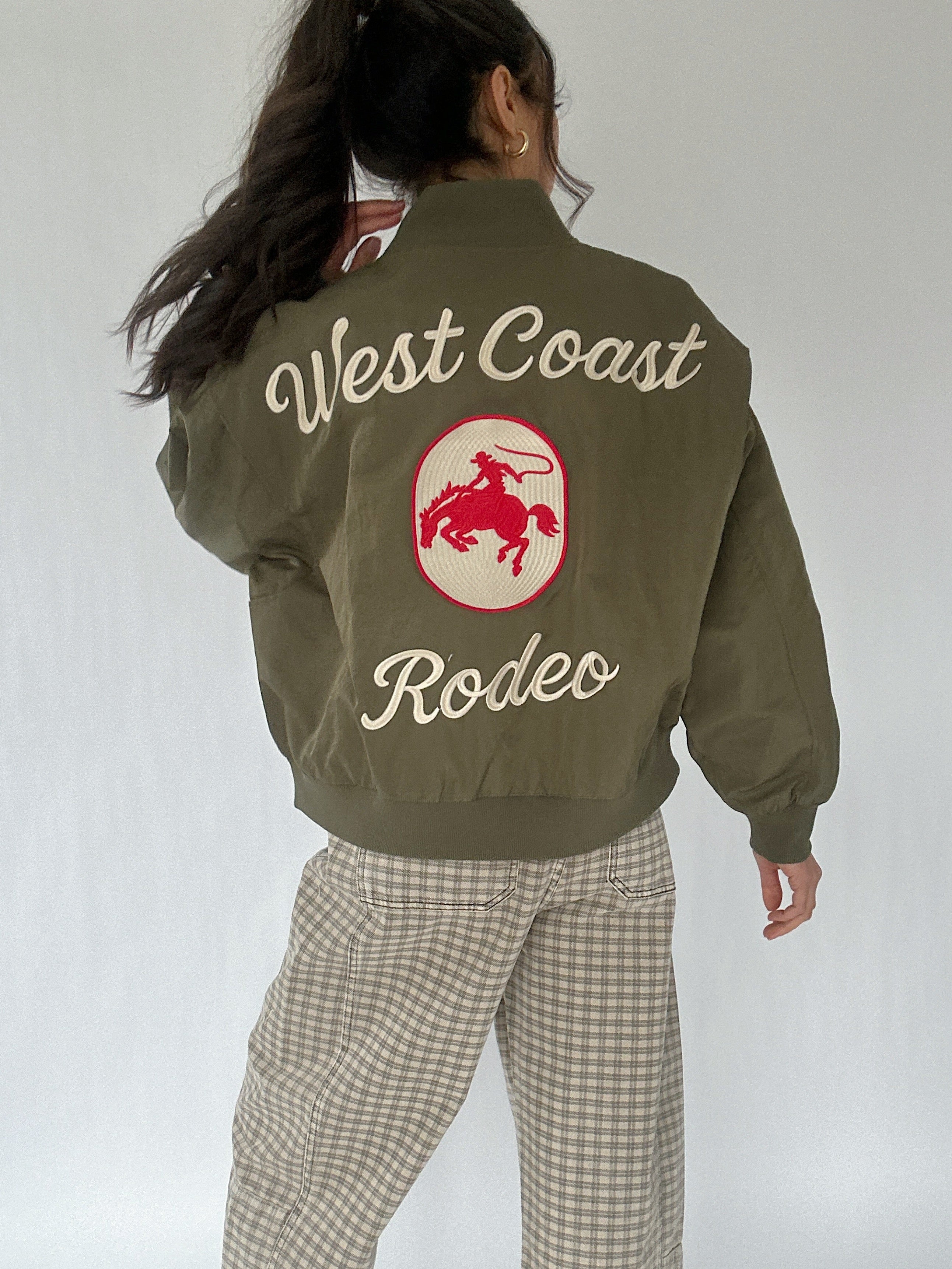 Person wearing a green jacket with 'West Coast Rodeo' text and logo on the back.