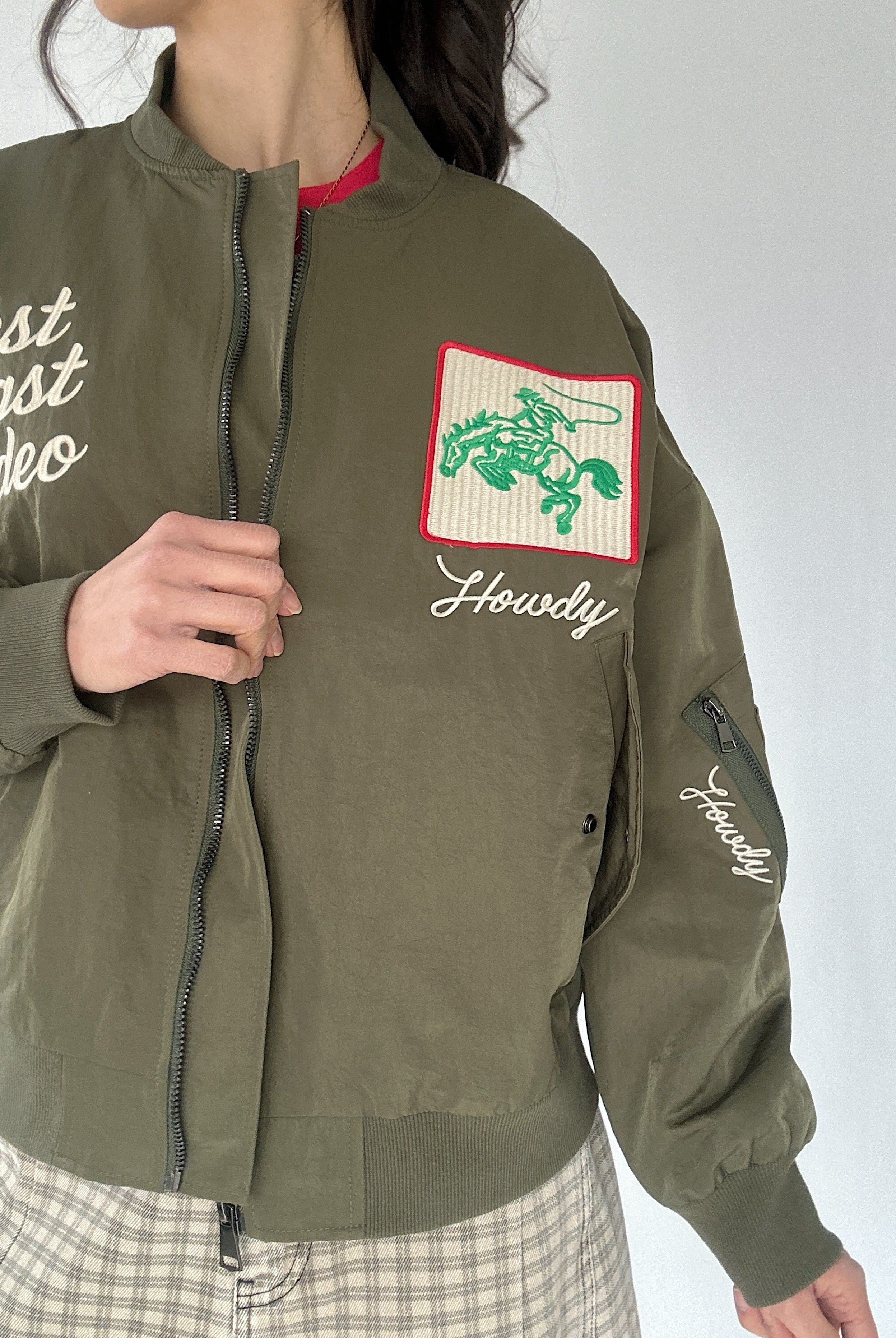 Green jacket with embroidered western designs on a plain background