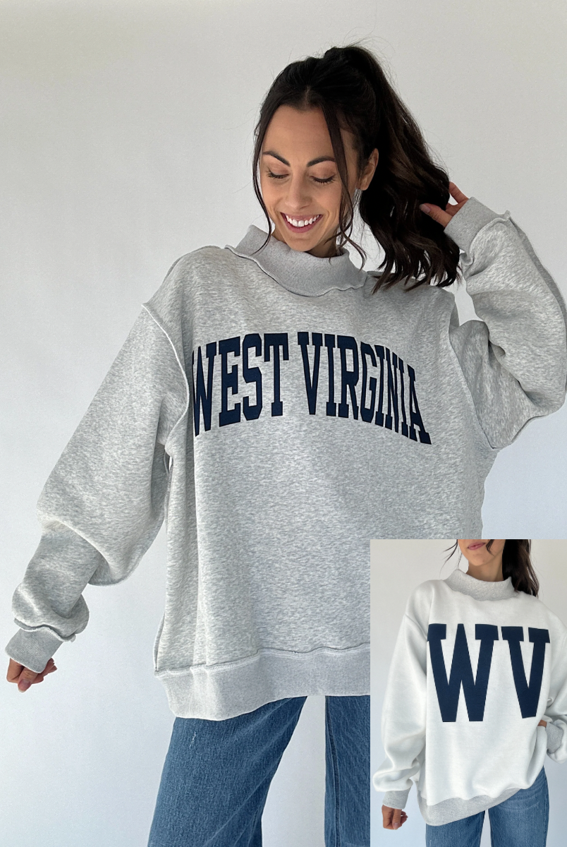Woman wearing a gray 'West Virginia' sweatshirt with a close-up of the 'WV' text on the reversible side a white background.