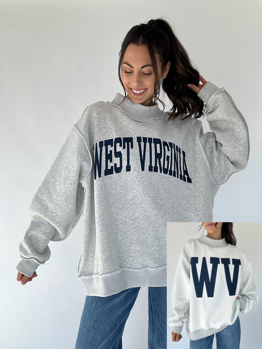 Woman wearing a gray 'West Virginia' sweatshirt with a close-up of the 'WV' text on the reversible side a white background.