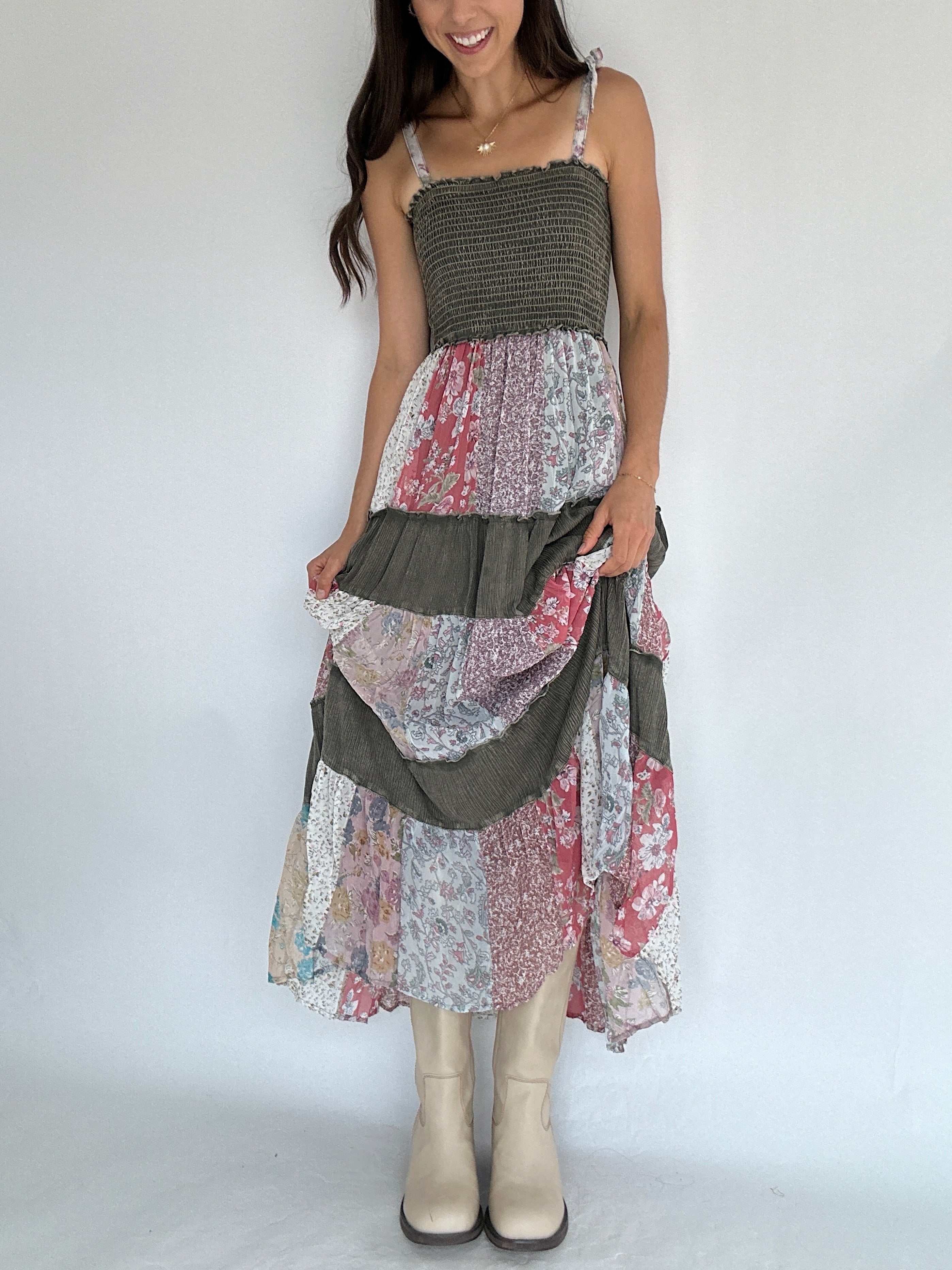 Woman wearing a patchwork dress with a plain background holding skirt