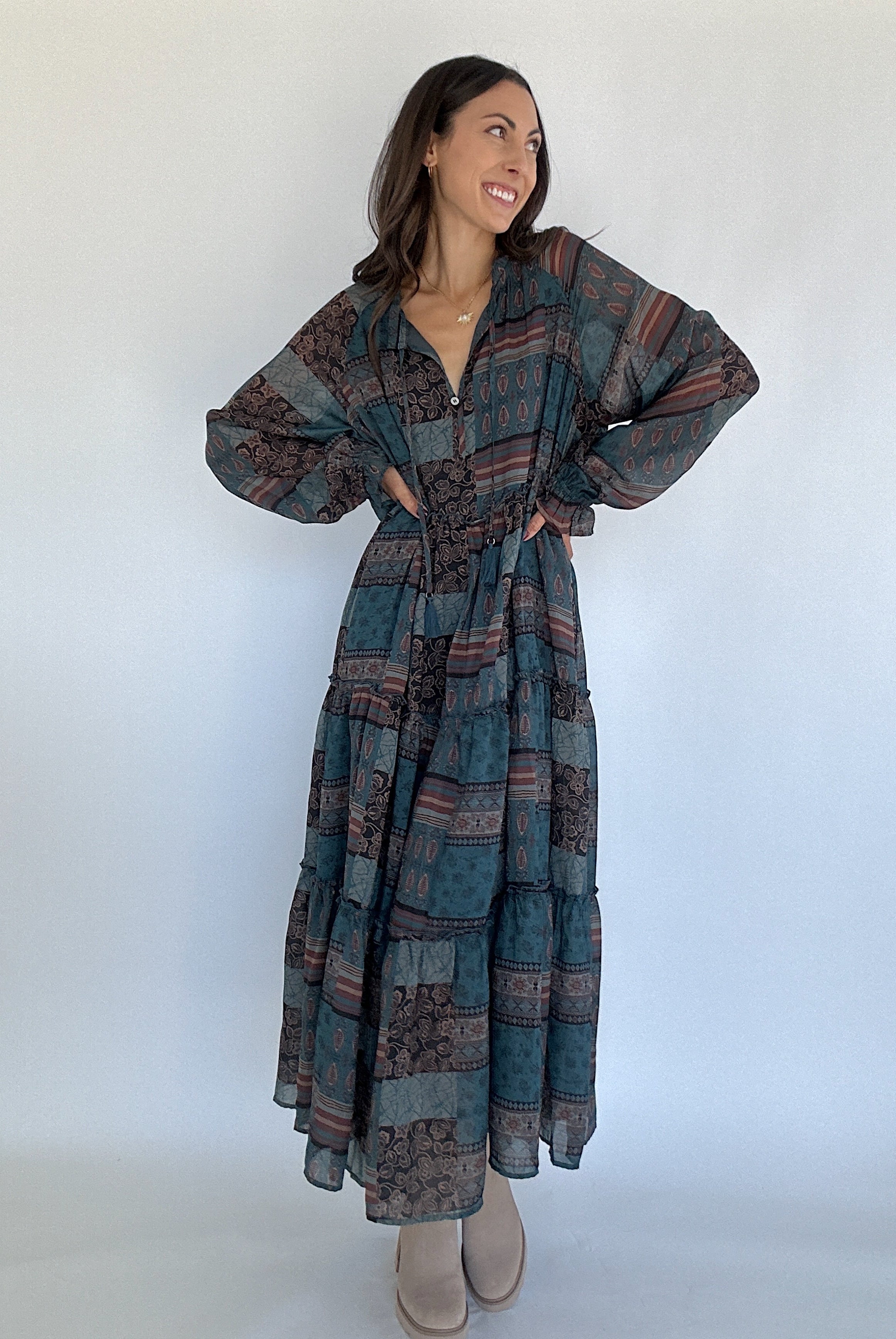 Woman wearing a long, patterned dress against a white background