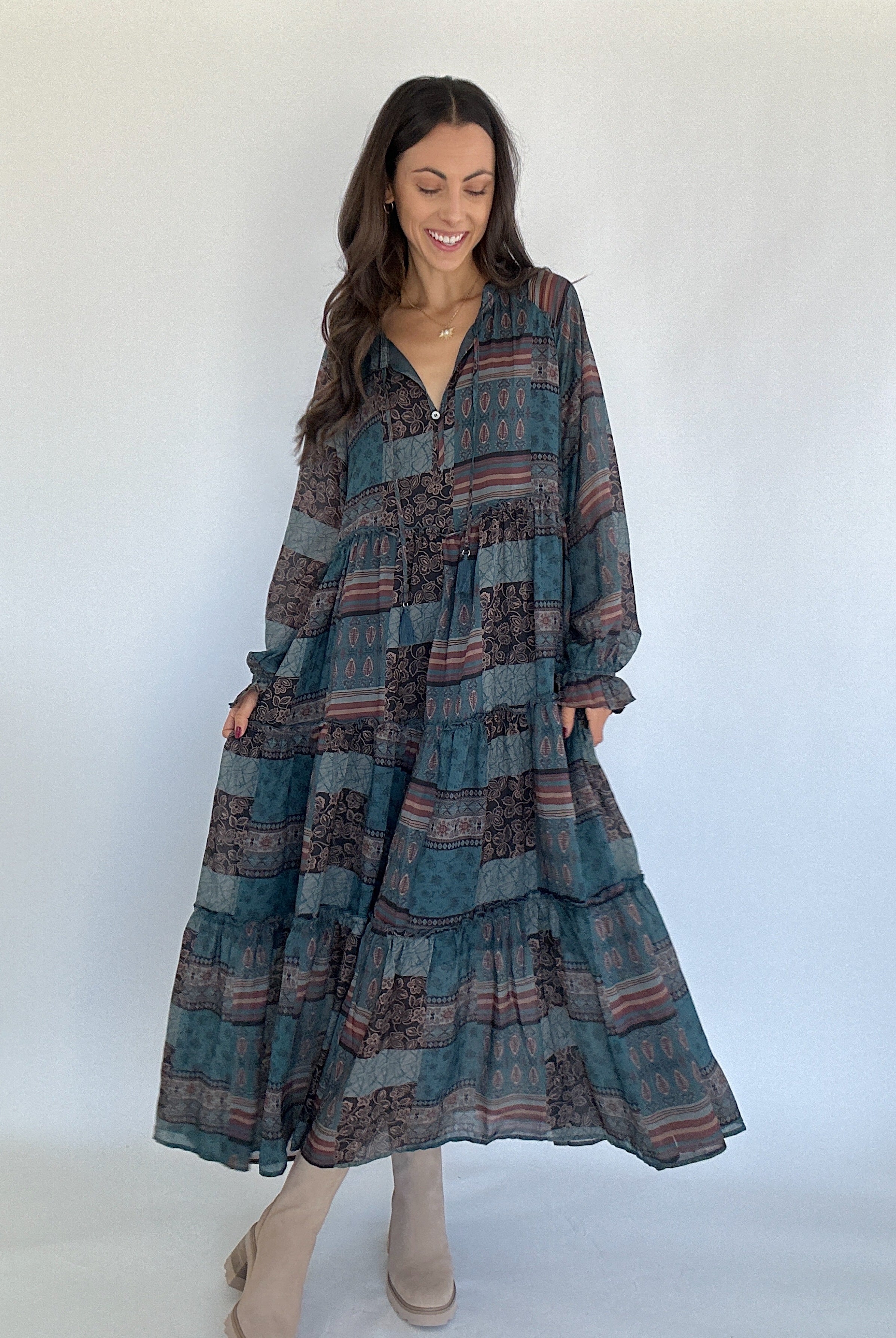 Woman wearing a long, patterned dress against a white background
