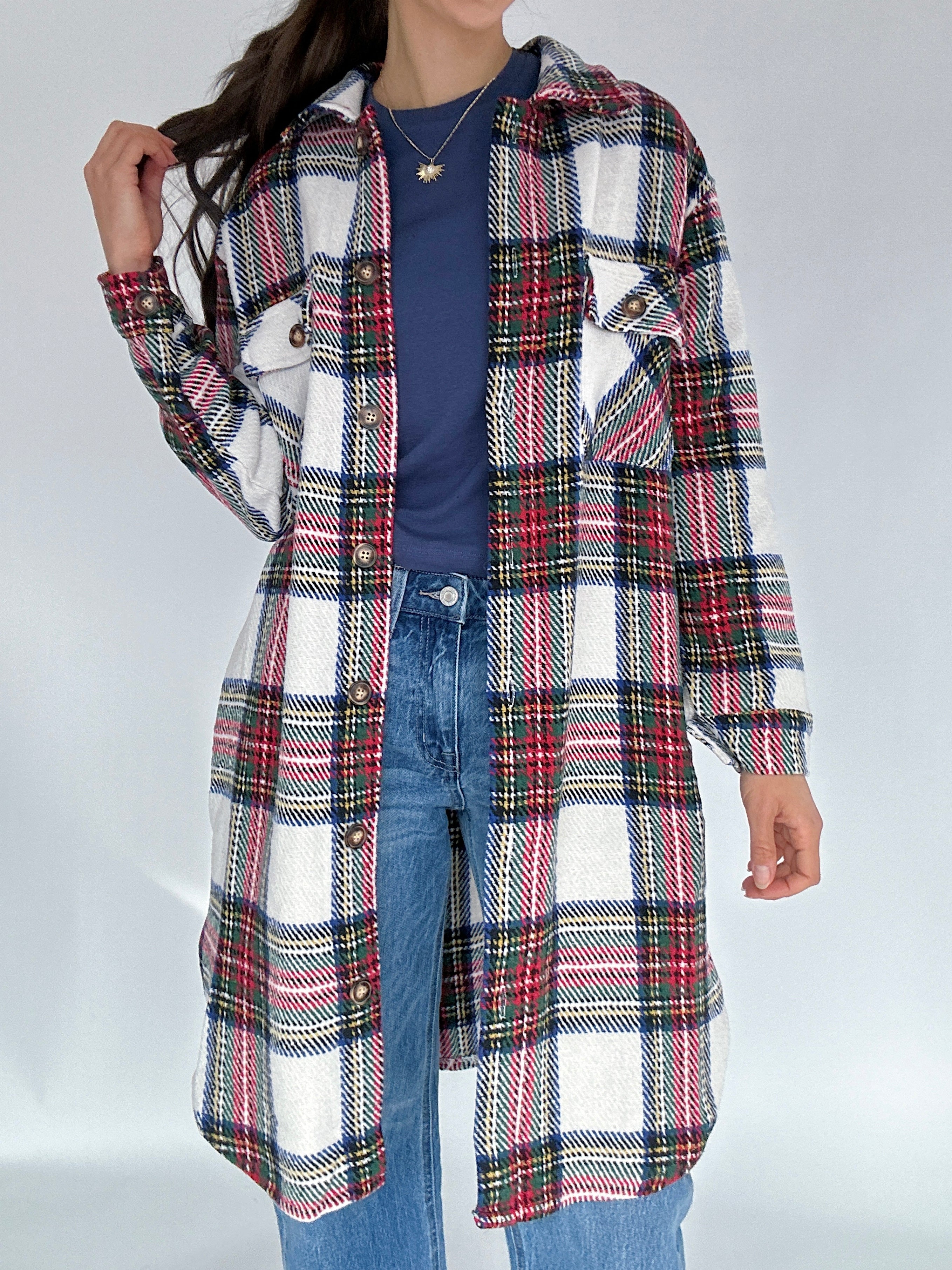 Person wearing a plaid coat over a blue shirt and jeans on a white background
