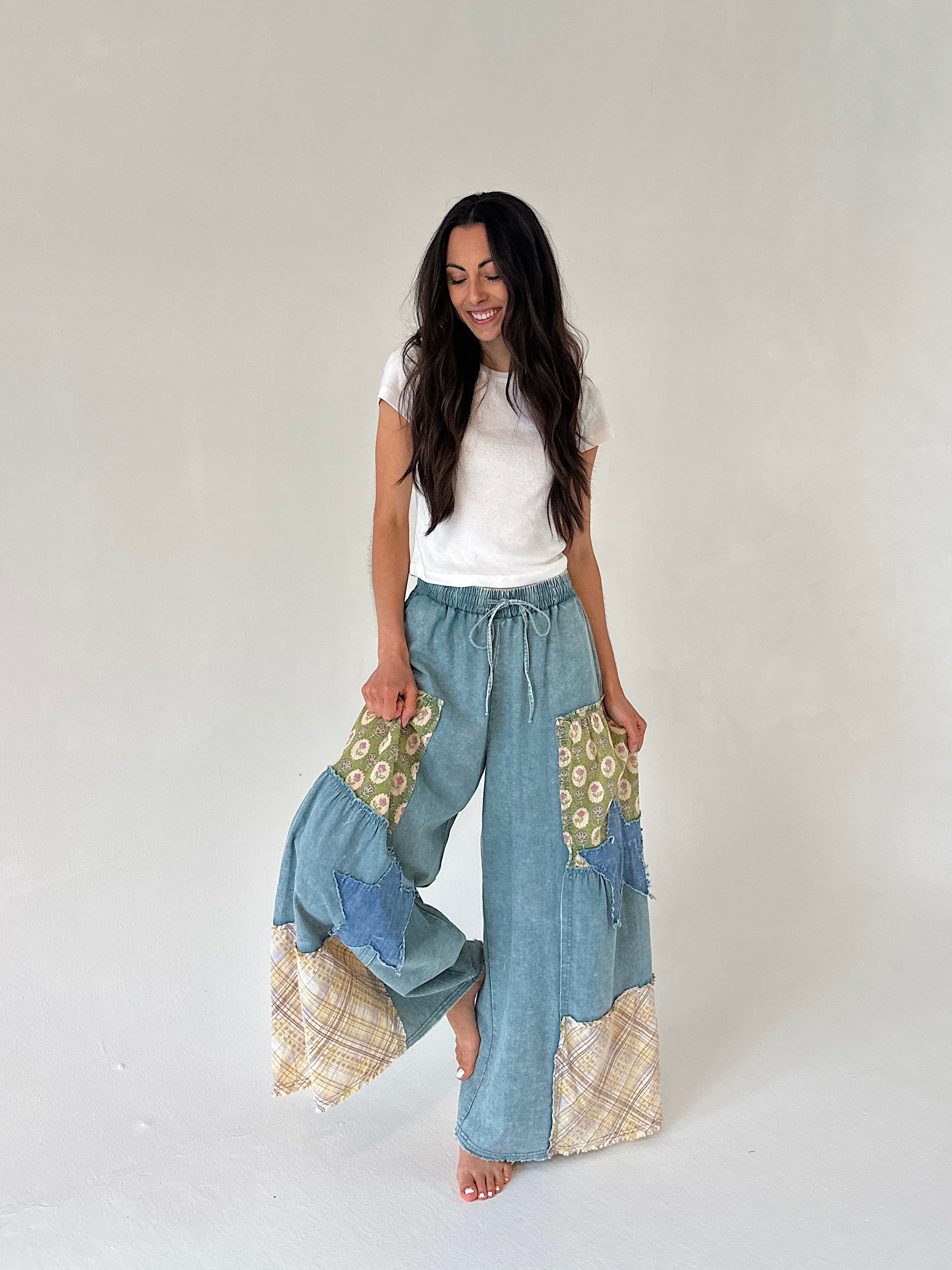 Woman wearing a white top and patchwork pants on a plain background
