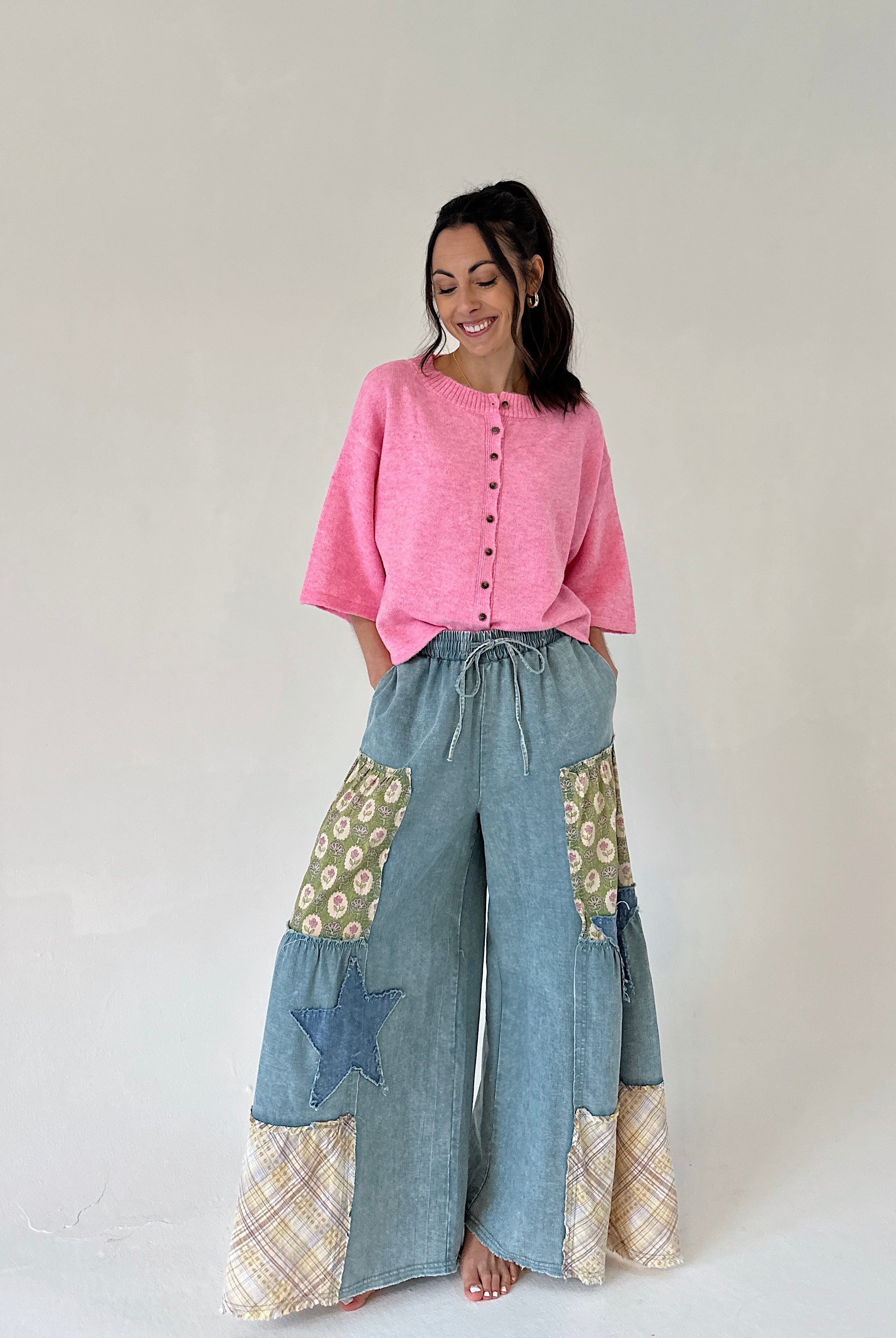Woman wearing a pink top and denim patchwork pants on a white background