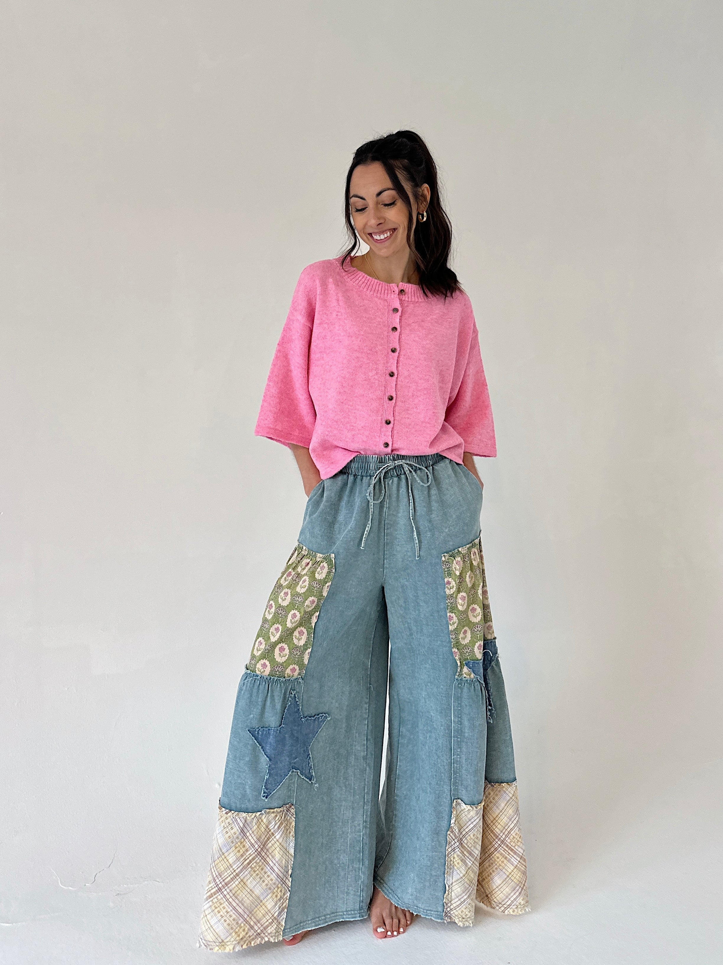 Woman wearing a pink top and denim patchwork pants on a white background