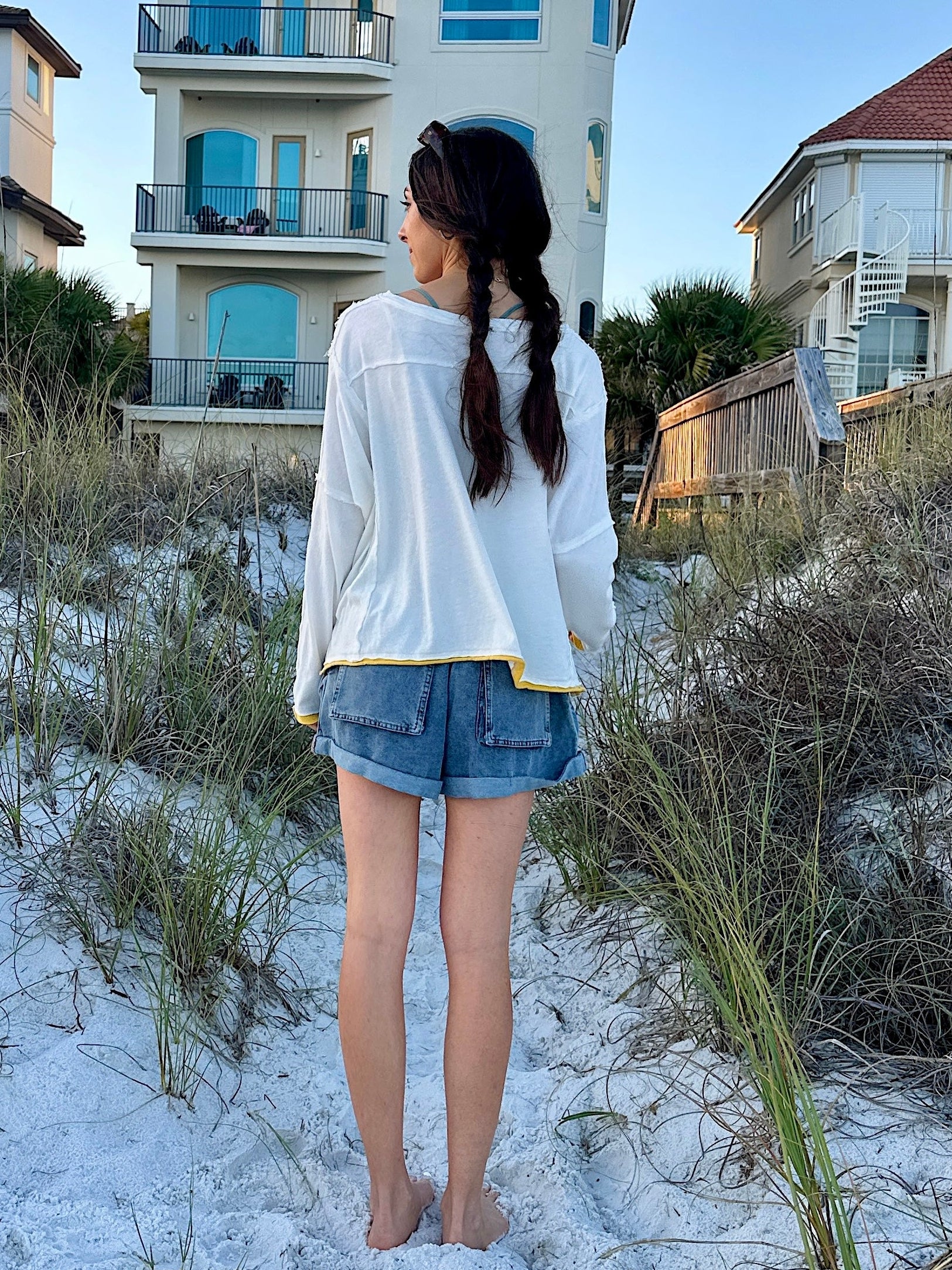 Woman standing on a sandy beach with houses in the background