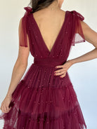 Maroon dress with self tie straps and a deep back neckline on a white background