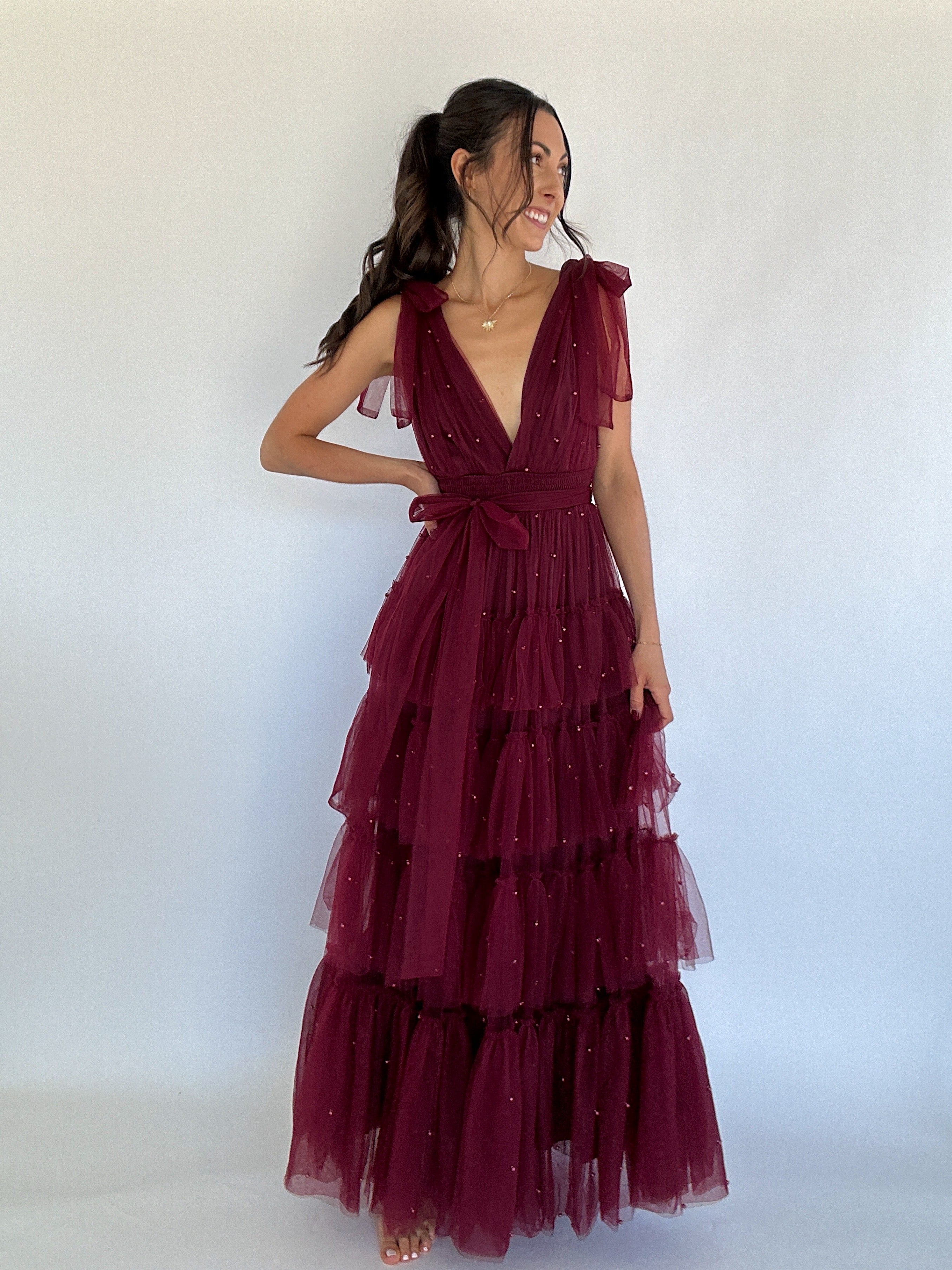 Woman wearing a burgundy tiered dress against a white background