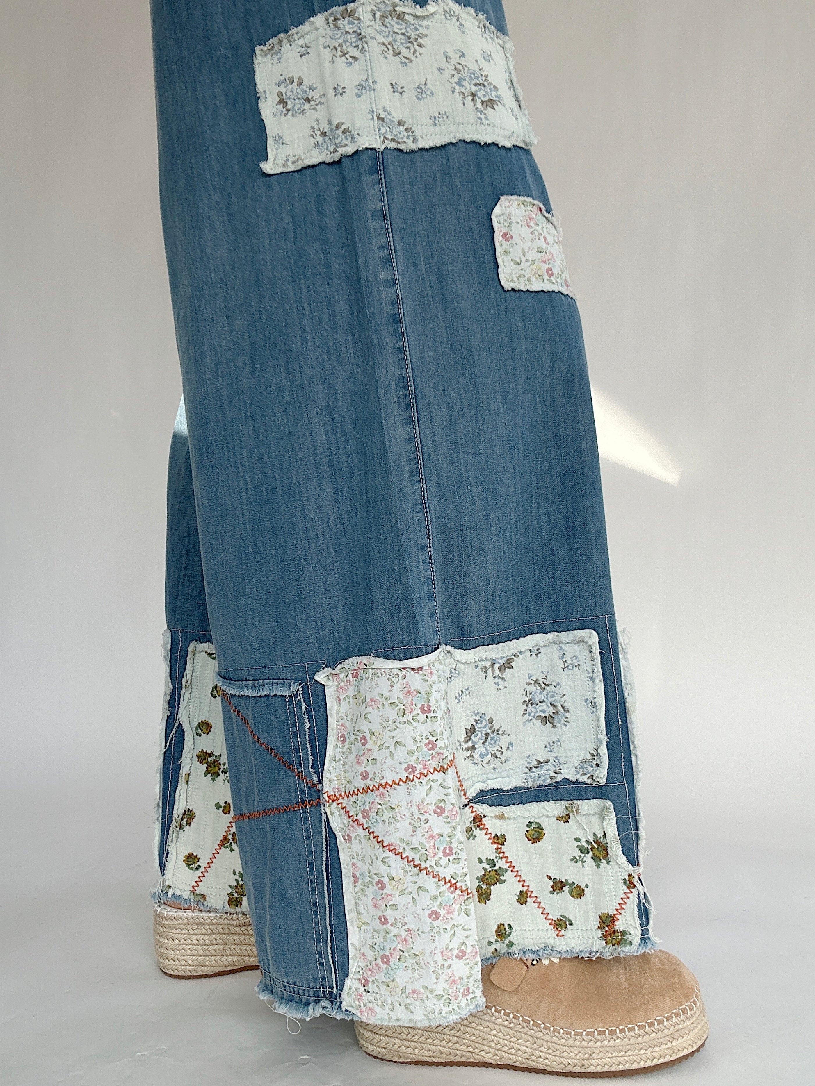 Blue jeans with floral patchwork on a white background to show the patch details