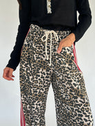 Leopard print pants with drawstring and red stripes on a plain background