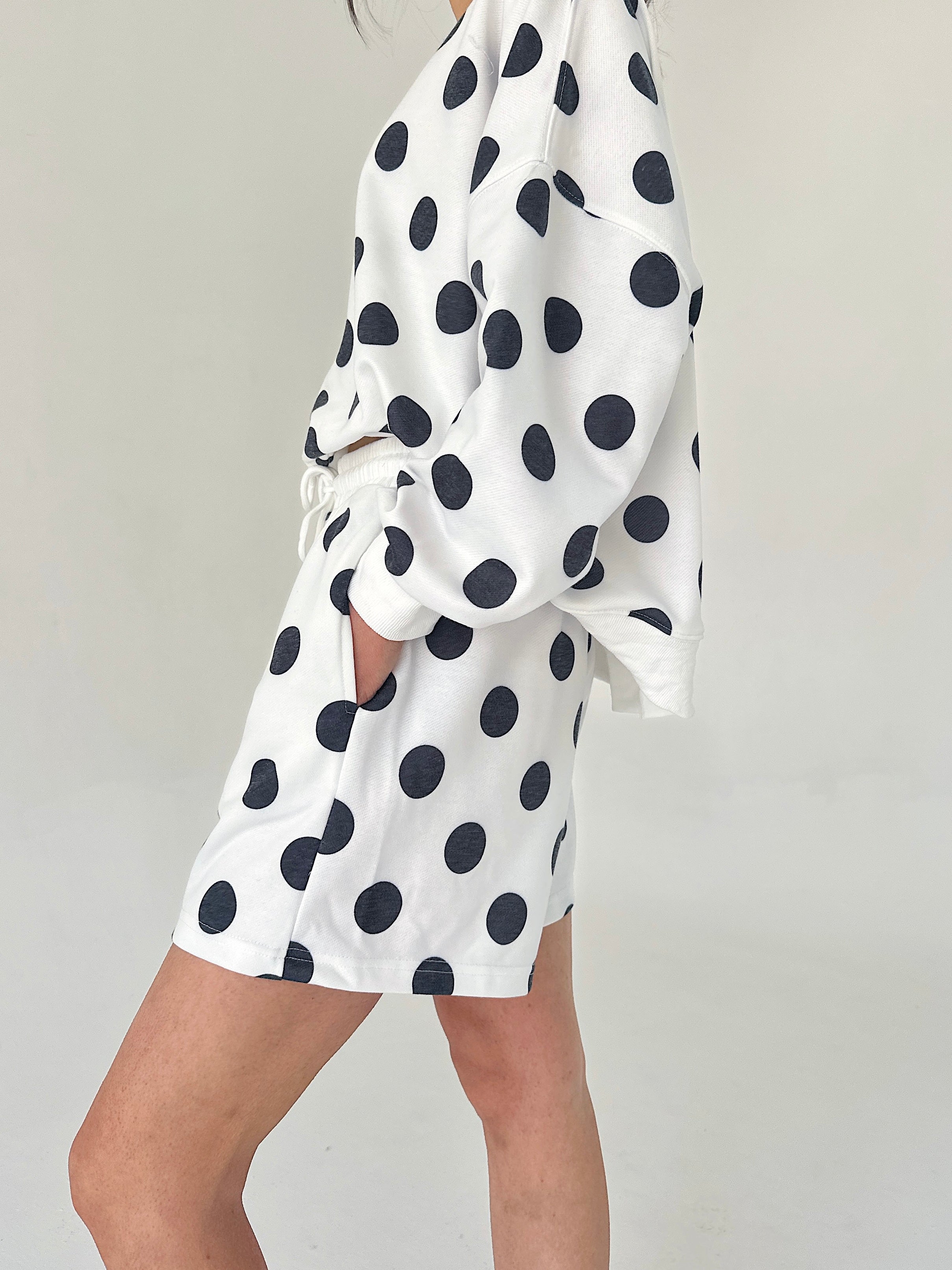 White dress with black polka dots on a plain background
