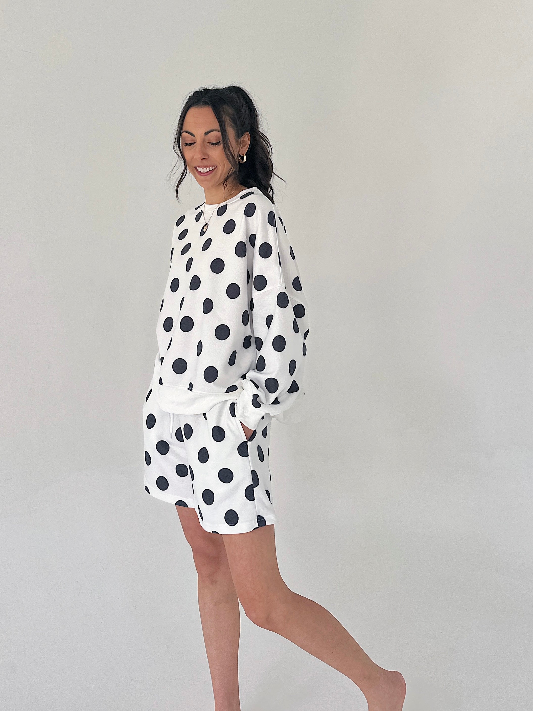 Woman wearing a white outfit with black polka dots on a plain background