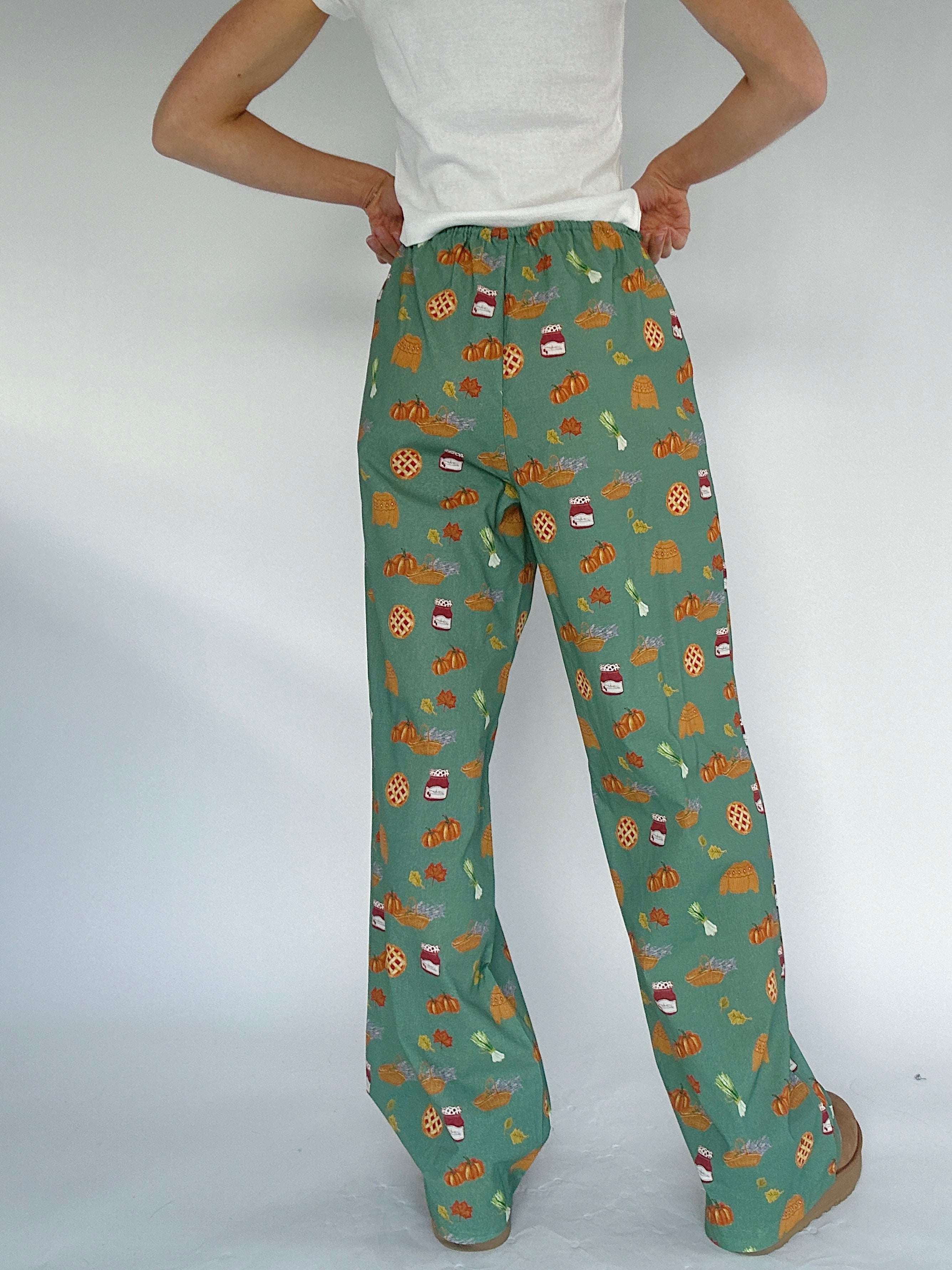 Green fall patterned pants worn by a person on a white background showing back