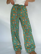 Green pants with autumn-themed pattern on a white background
