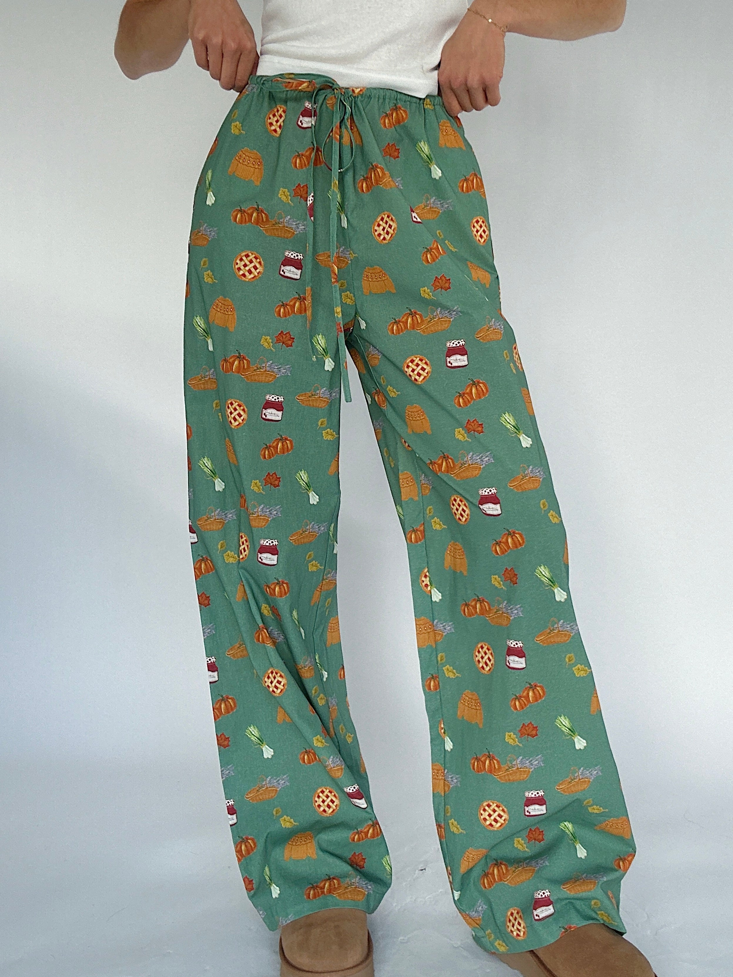 Green pants with autumn-themed pattern on a white background