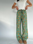 Person wearing green pants with fall inspired pattern on a white background