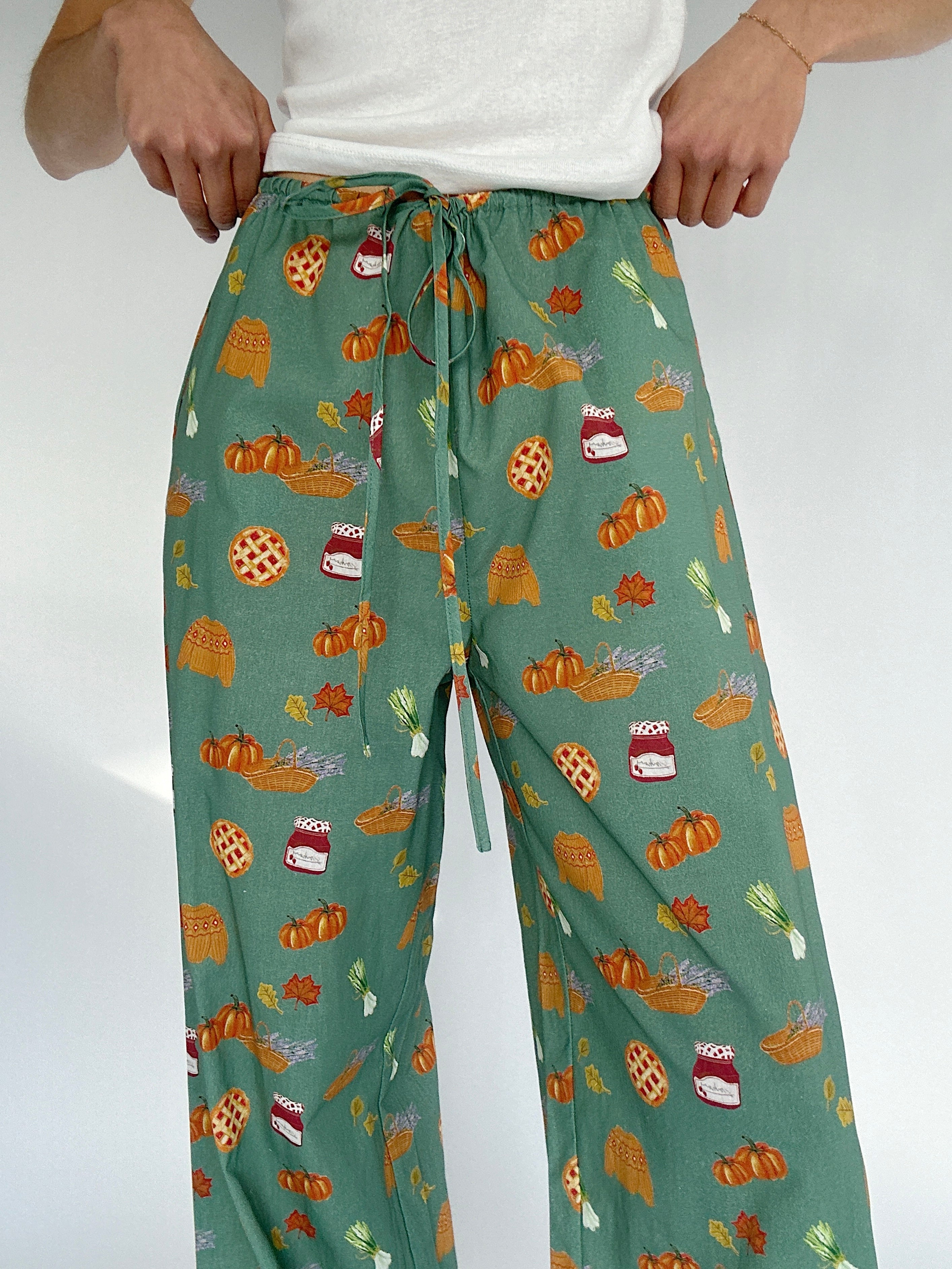 Green pants with autumn-themed pattern on a white background showing drawstring waist
