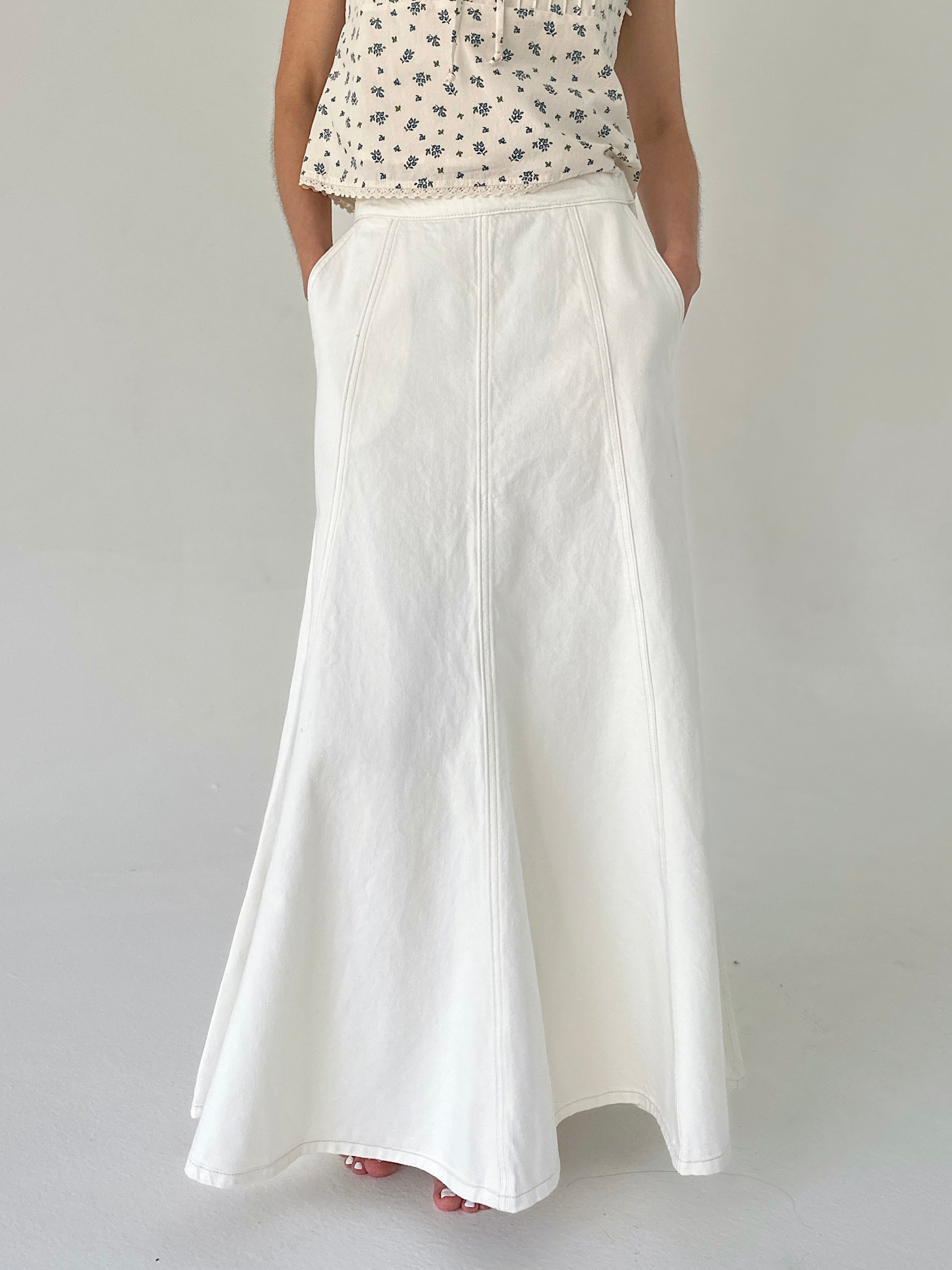 Person wearing a white skirt and patterned top on a plain background