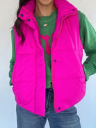 Hot pink puffer vest over a green sweater