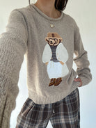 Person wearing a sweater with a dressed up teddy bear design on a white background - selfie version