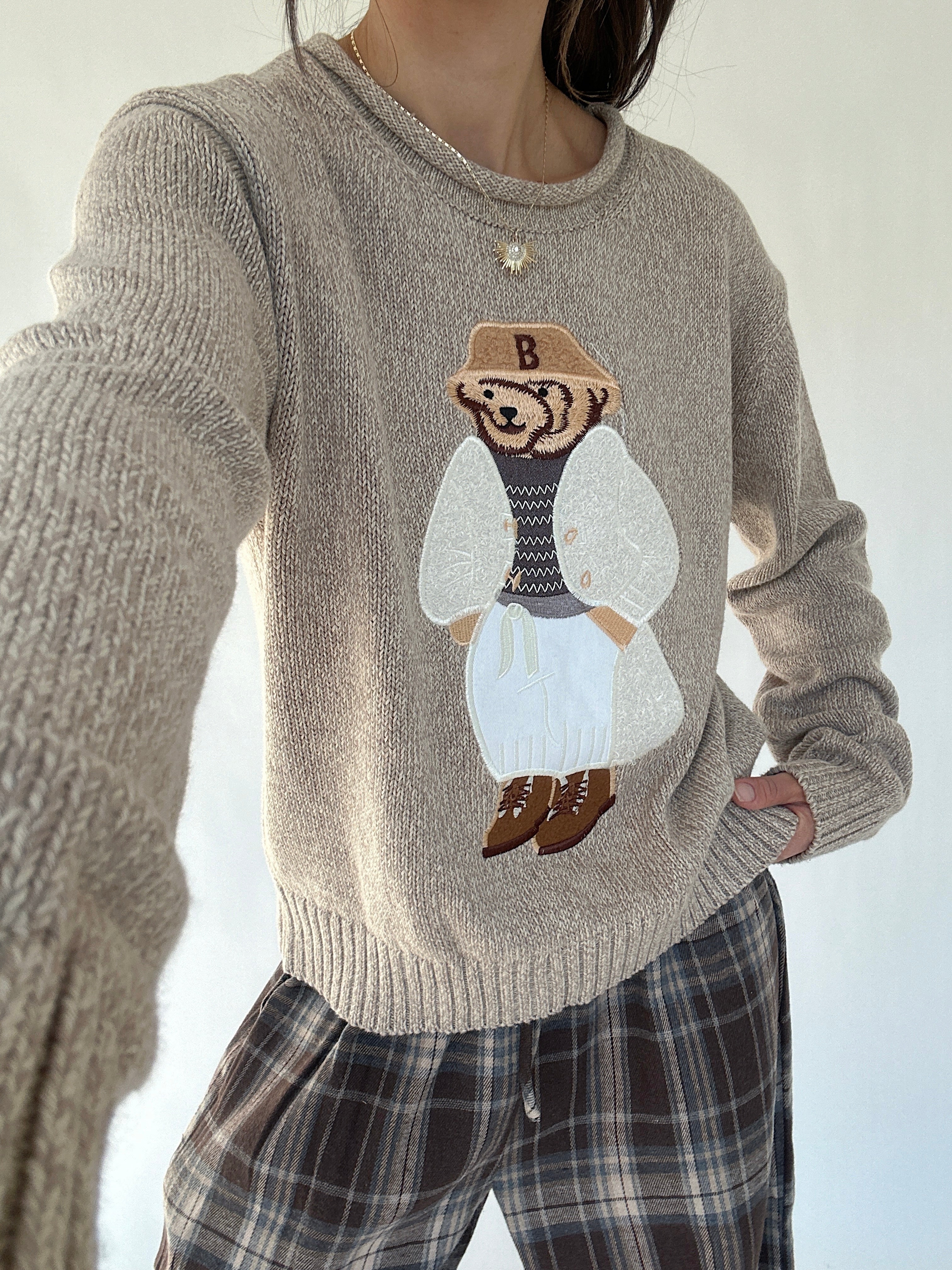 Person wearing a sweater with a dressed up teddy bear design on a white background - selfie version