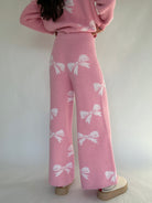 Person wearing a pink outfit with white bow patterns on a plain background showing back of pants