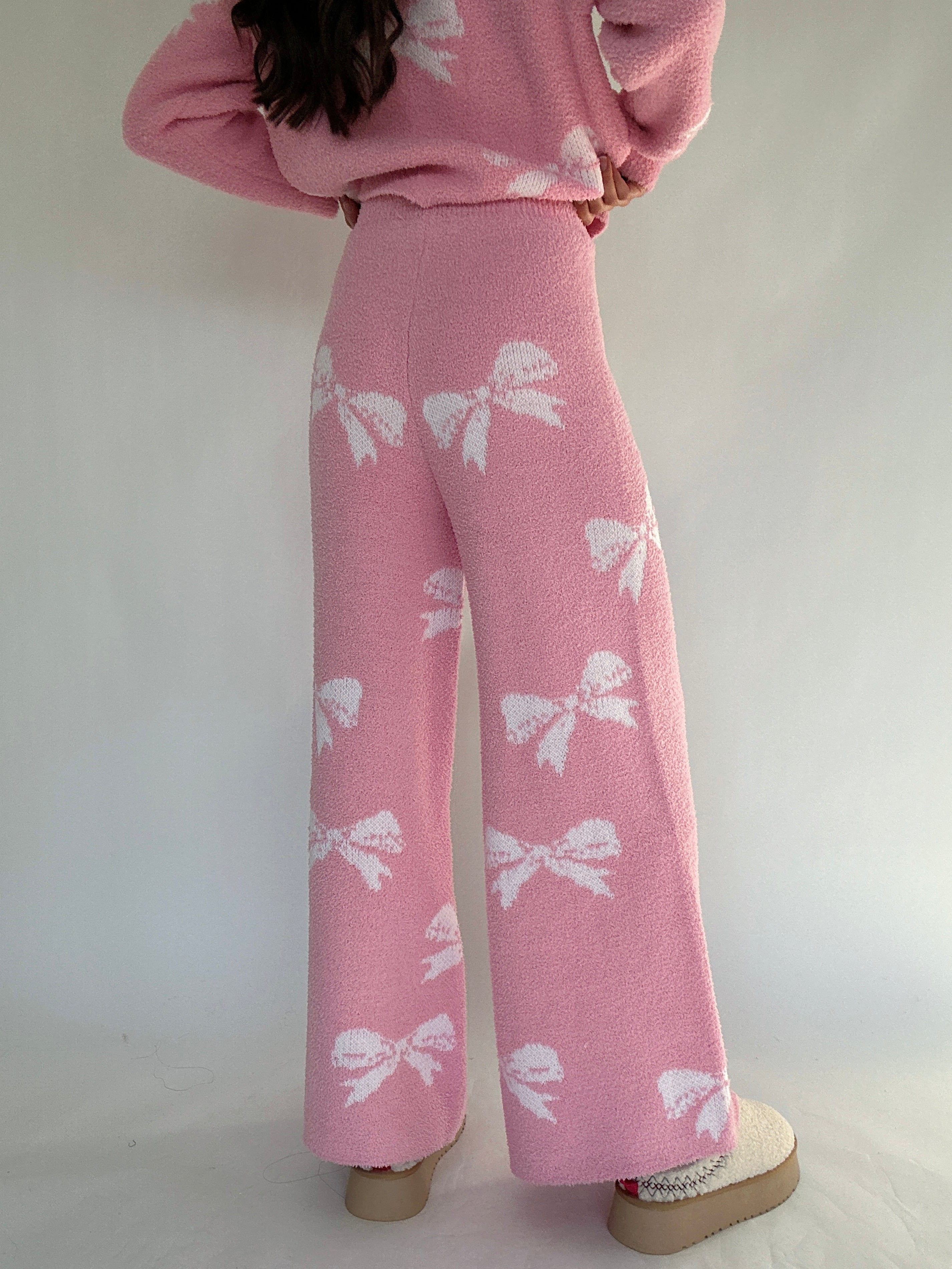 Person wearing a pink outfit with white bow patterns on a plain background showing back of pants