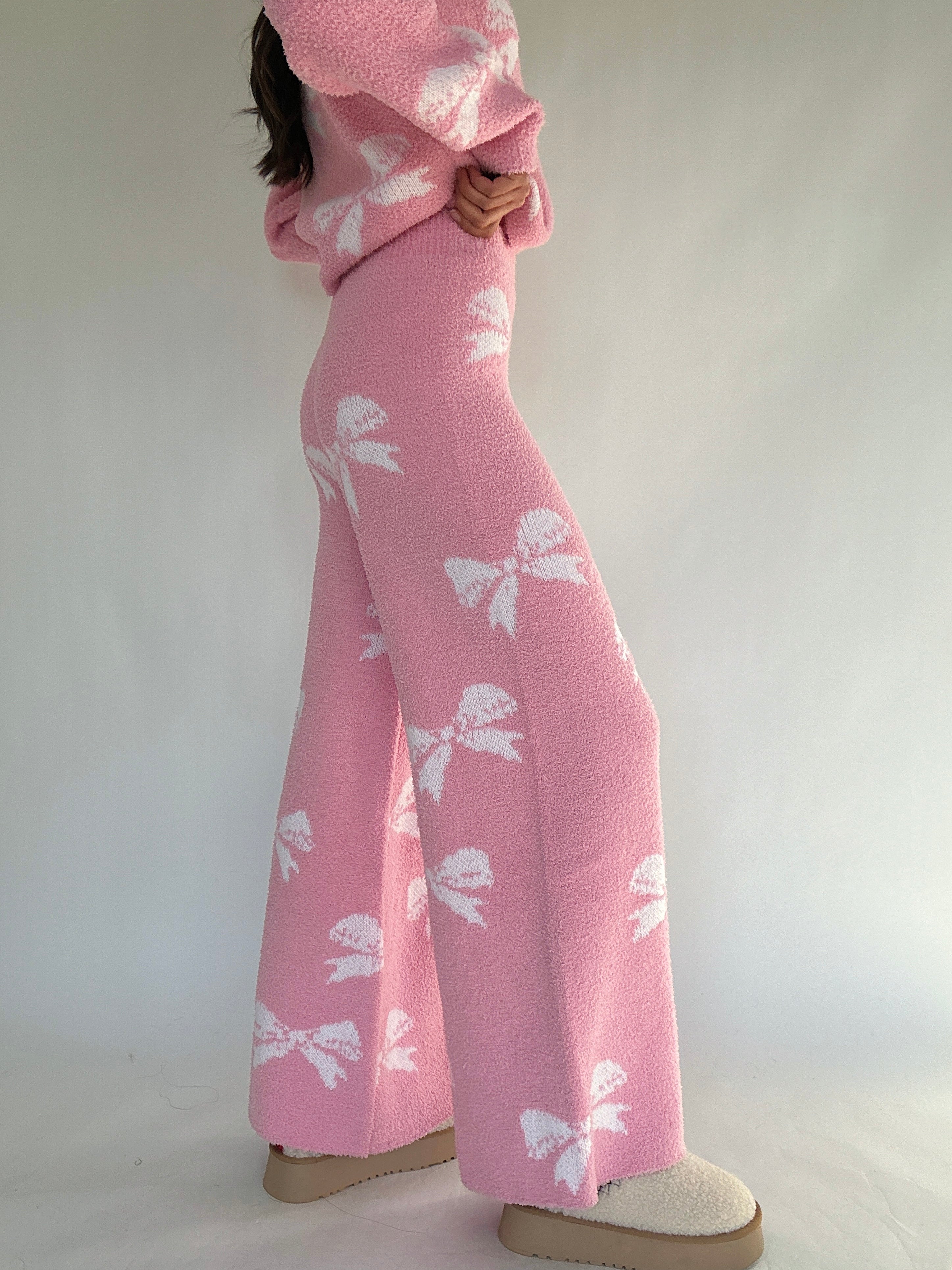 Person wearing a pink outfit with white bow pattern on a plain background showing side of pants