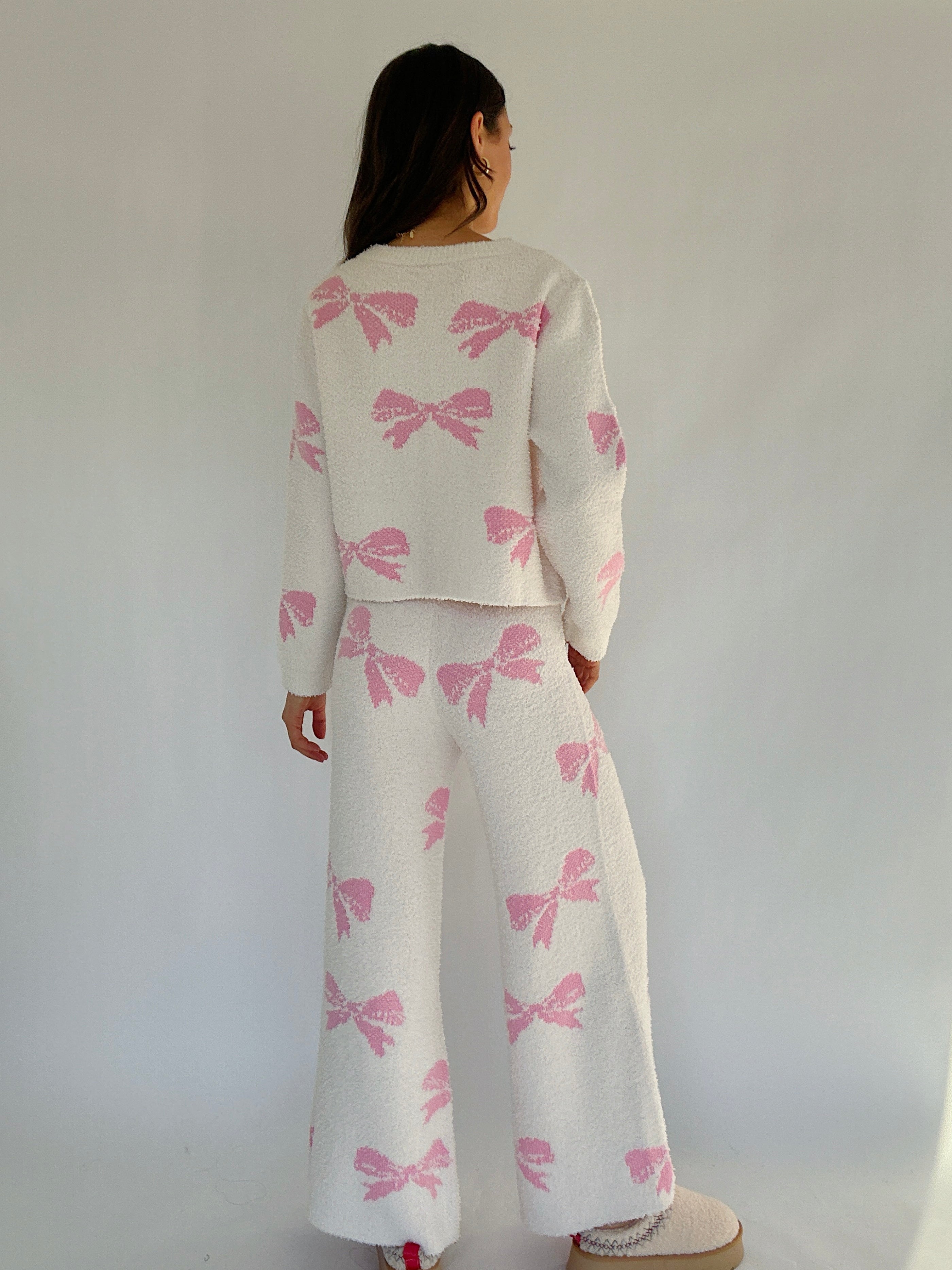 Person wearing a cream outfit with pink bow patterns against a plain background showing back