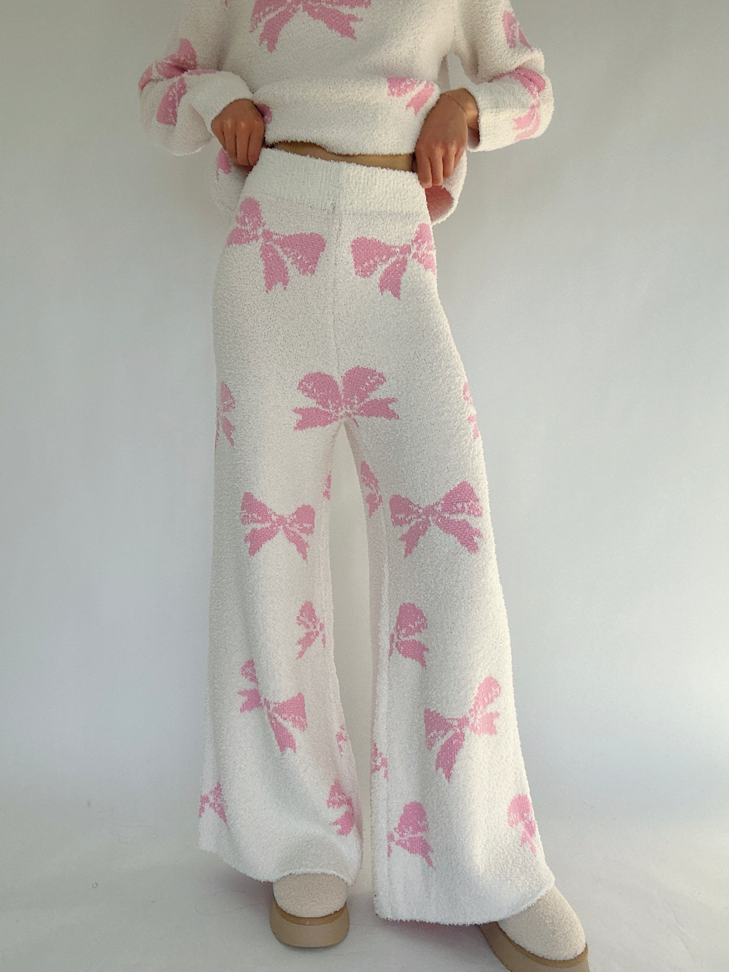 White outfit with pink bow pattern on a plain background showing front of pants