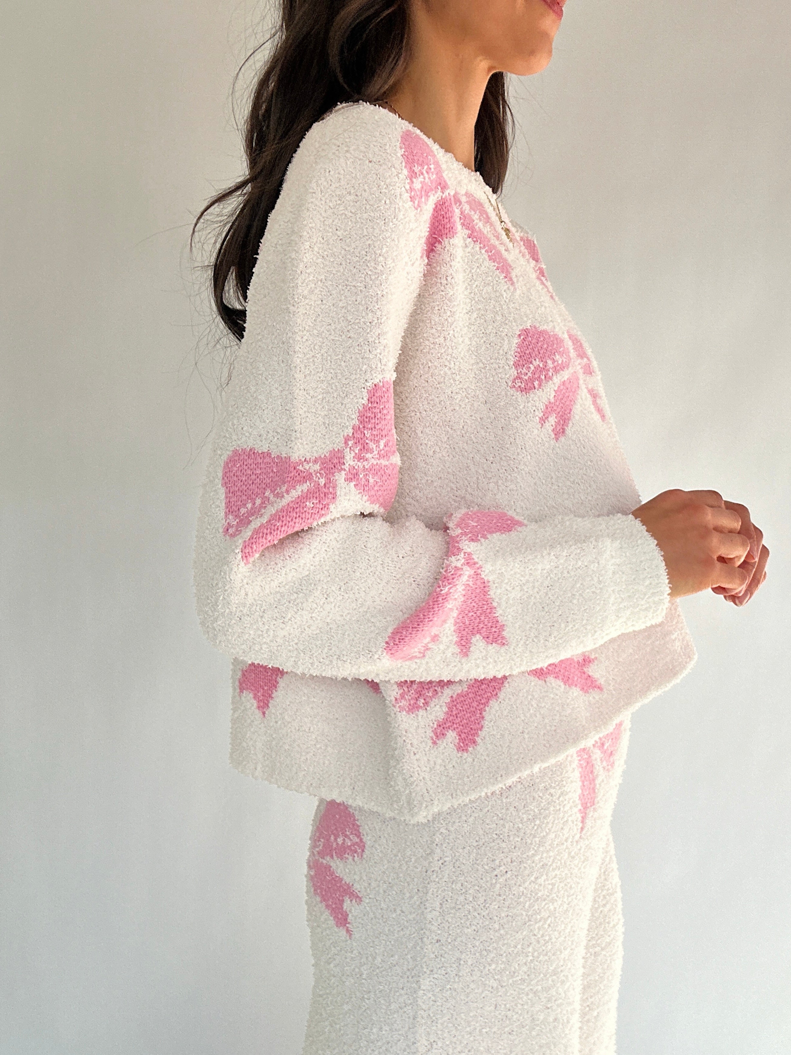 White outfit with pink bow patterns on a plain background side of top